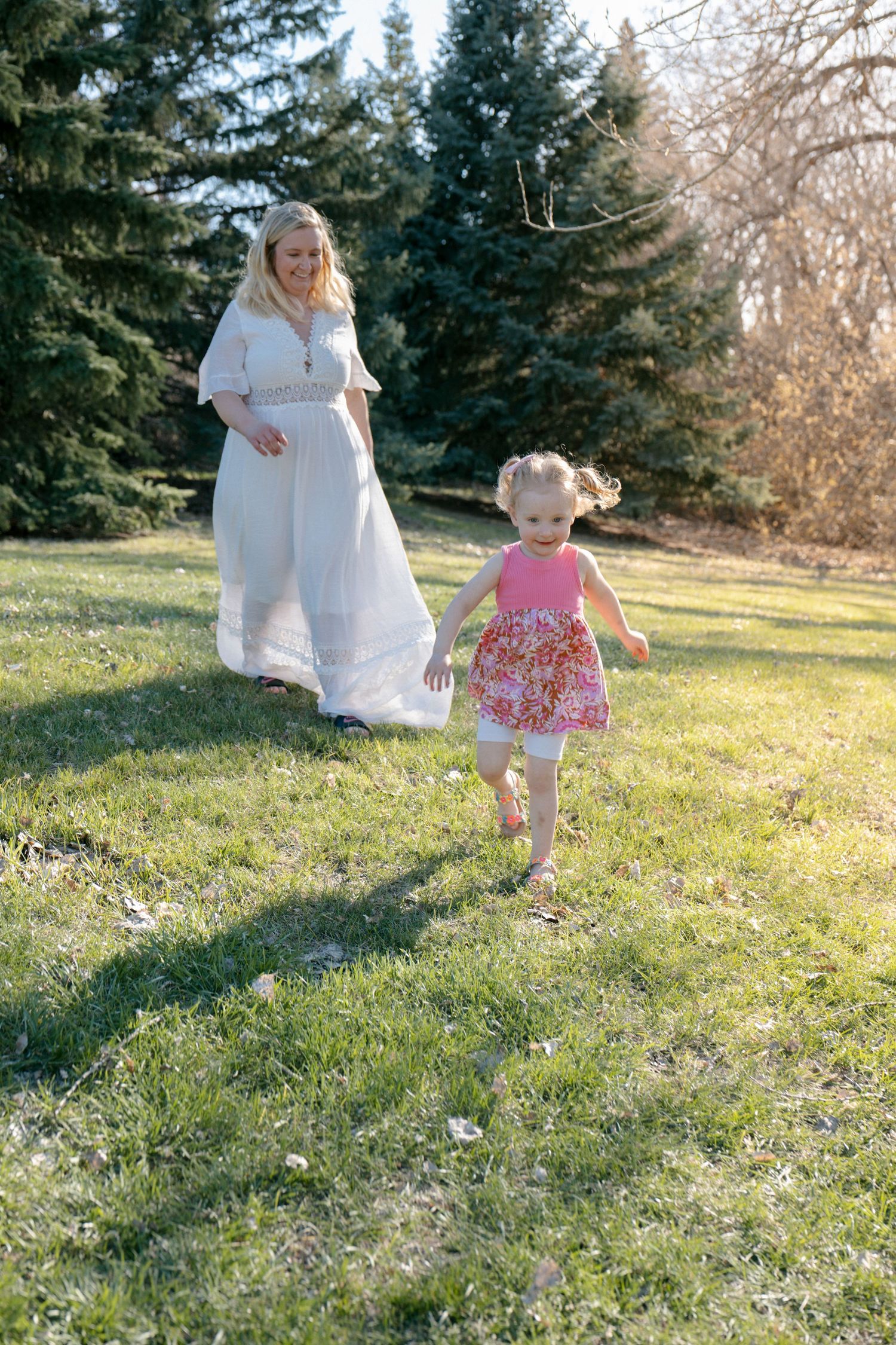 mom chasing daughter as she laughs and runs in sunny park in Bismarck