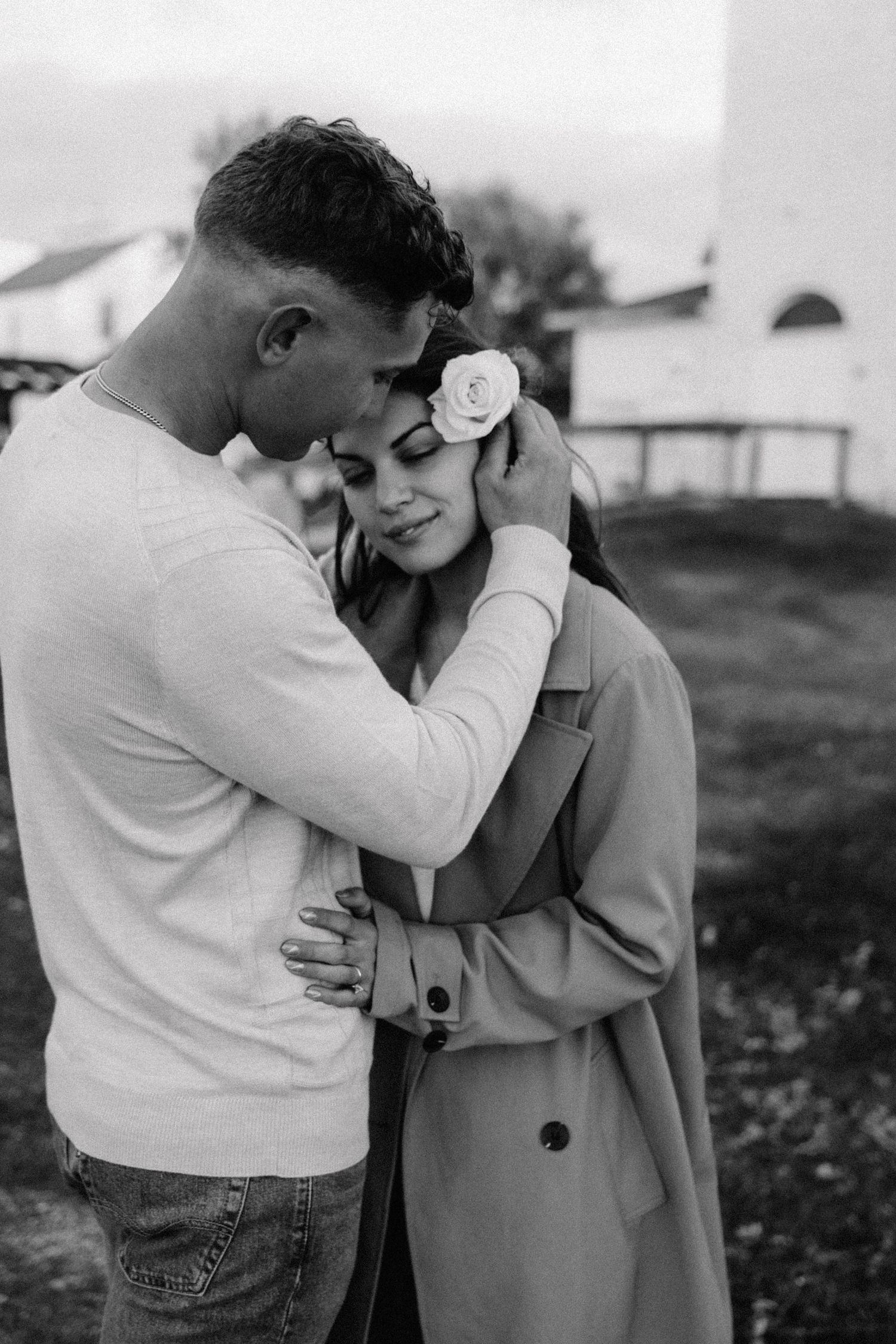 engagement session with man putting flower in hair of girl