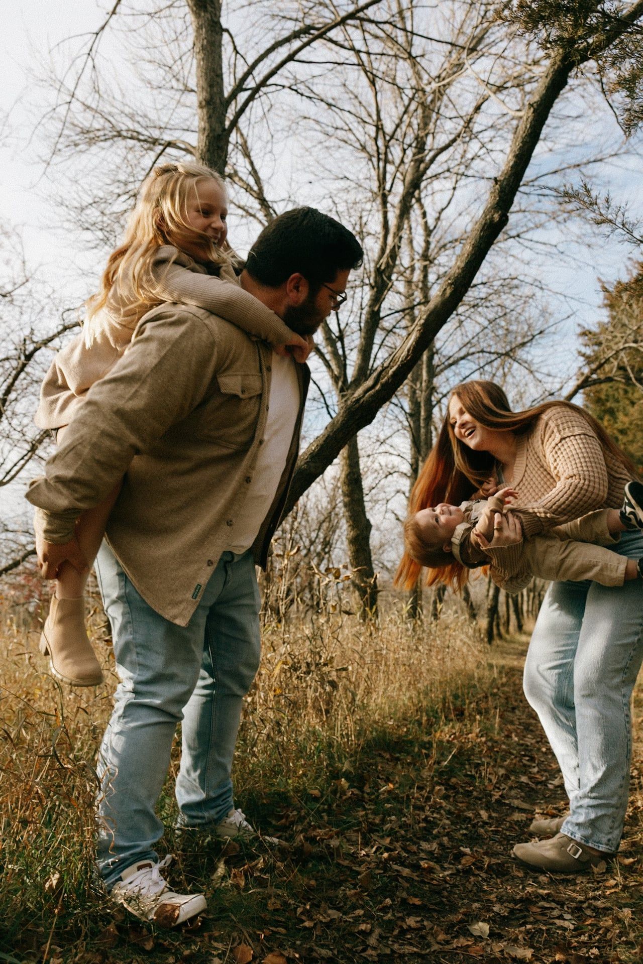 mom dipping baby back for giggles and dad with daughter on back as she laughs