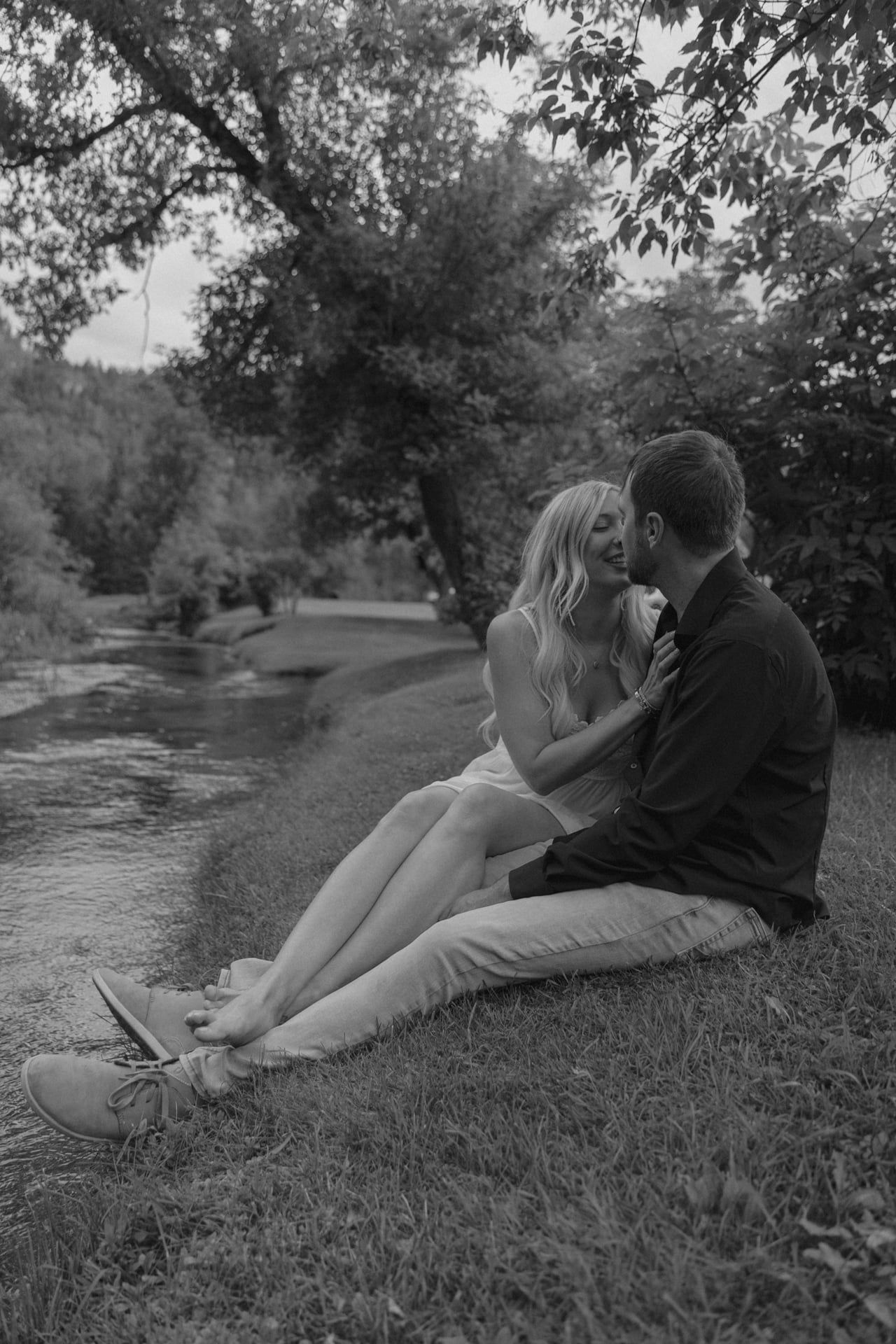 couple kissing each other in black hills for engagement session by water stream