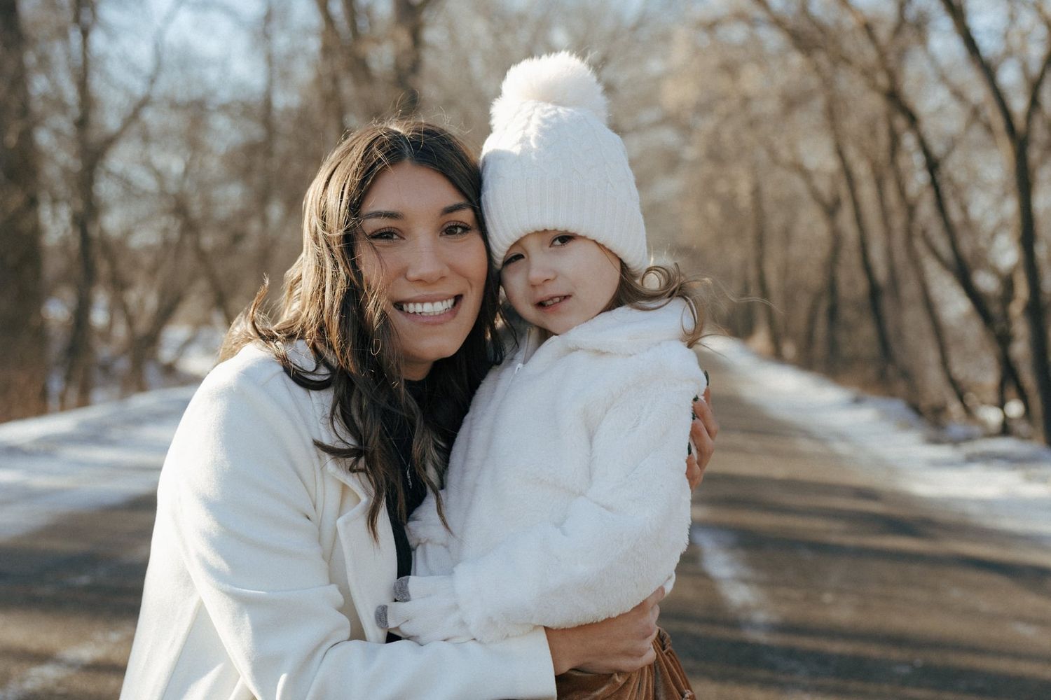 photos of mother to be crouching down next to daughter in snowy trees in Bismarck