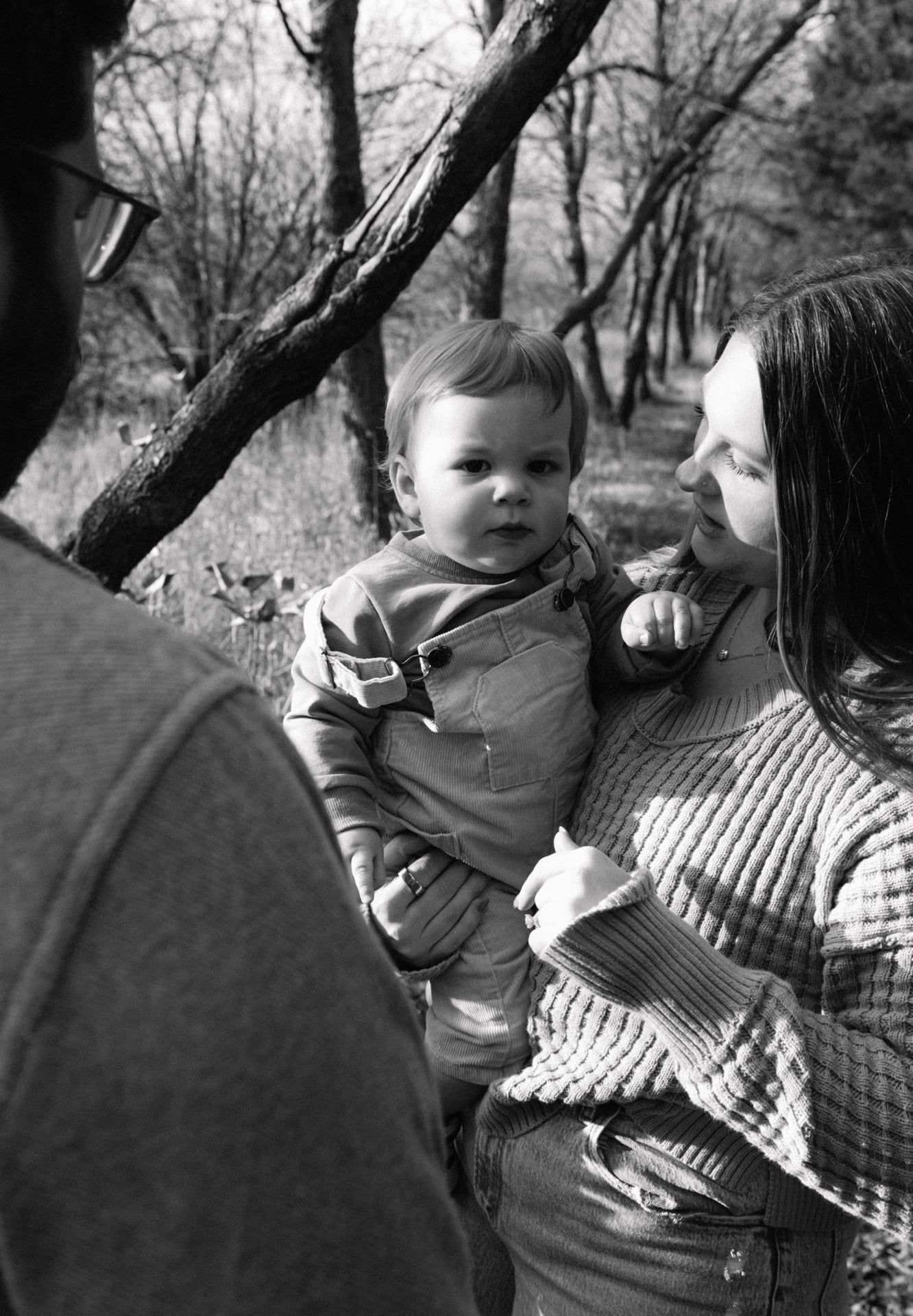 mom holding baby as dad looks at them and mom looks at baby