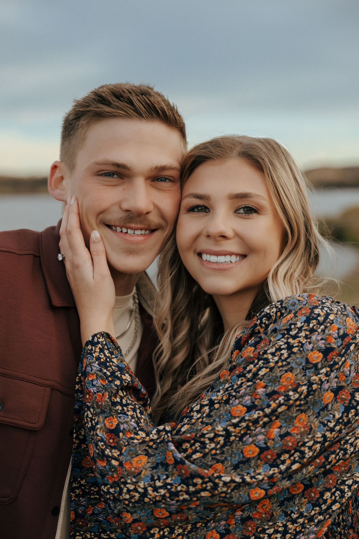 Close-up portrait of happy couple against natural landscape backdrop.