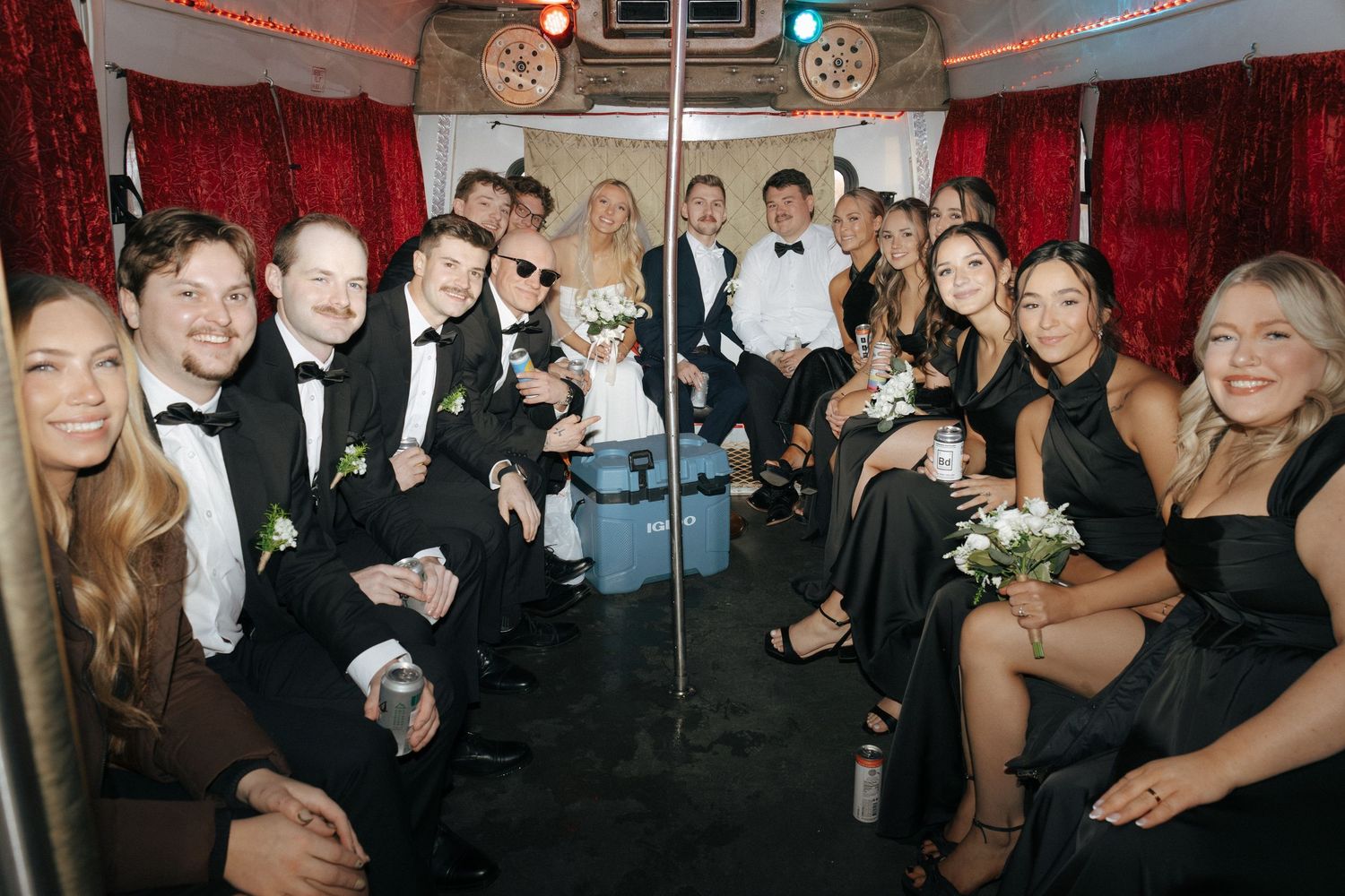 Wedding reception party scene with red curtains and guests mingling in formal attire.