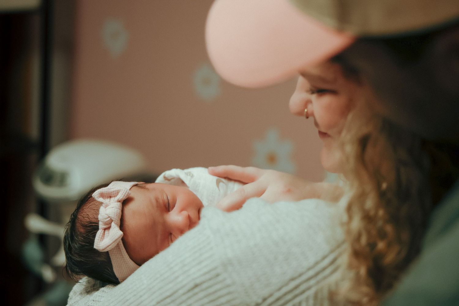 mom and dad looking down at newborn at home in nursery