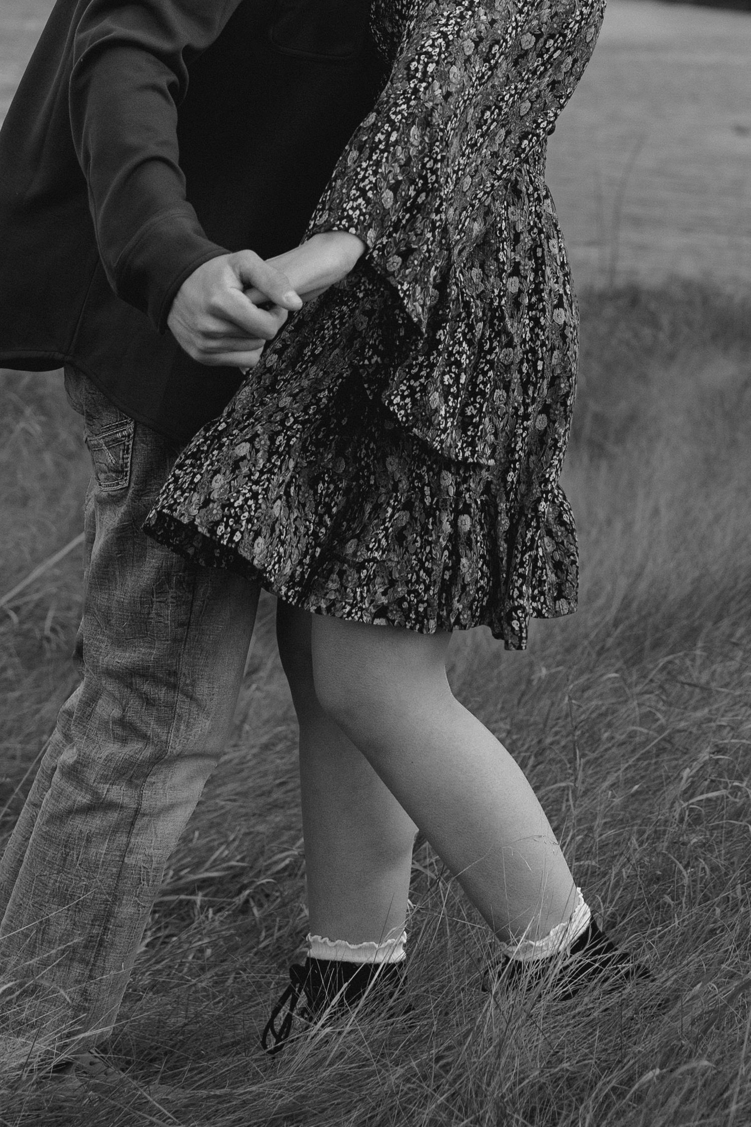 Black and white detail shot of couple's legs in grass field.
