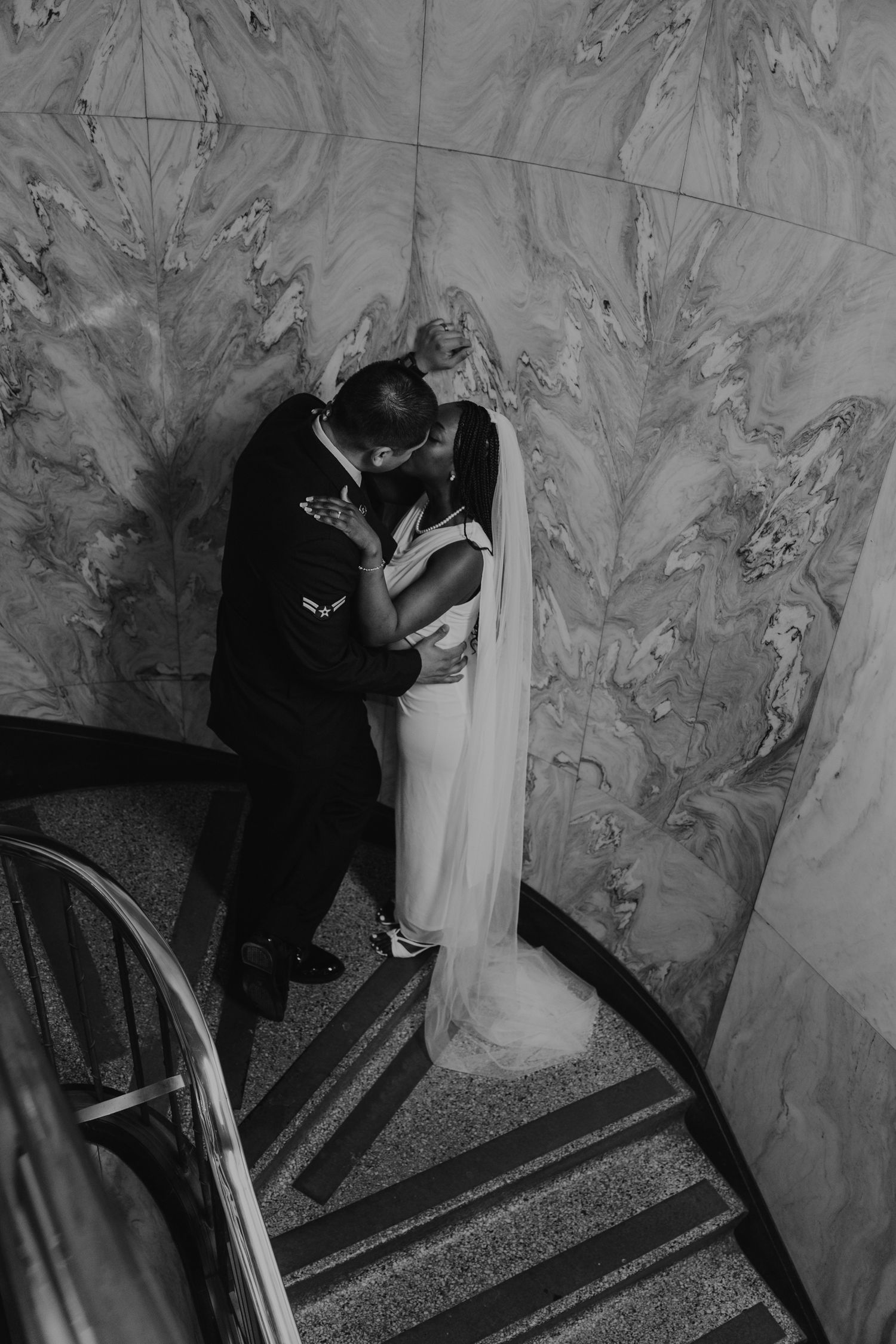 Black and white photos of a couple descending marble stairs with dramatic lighting.