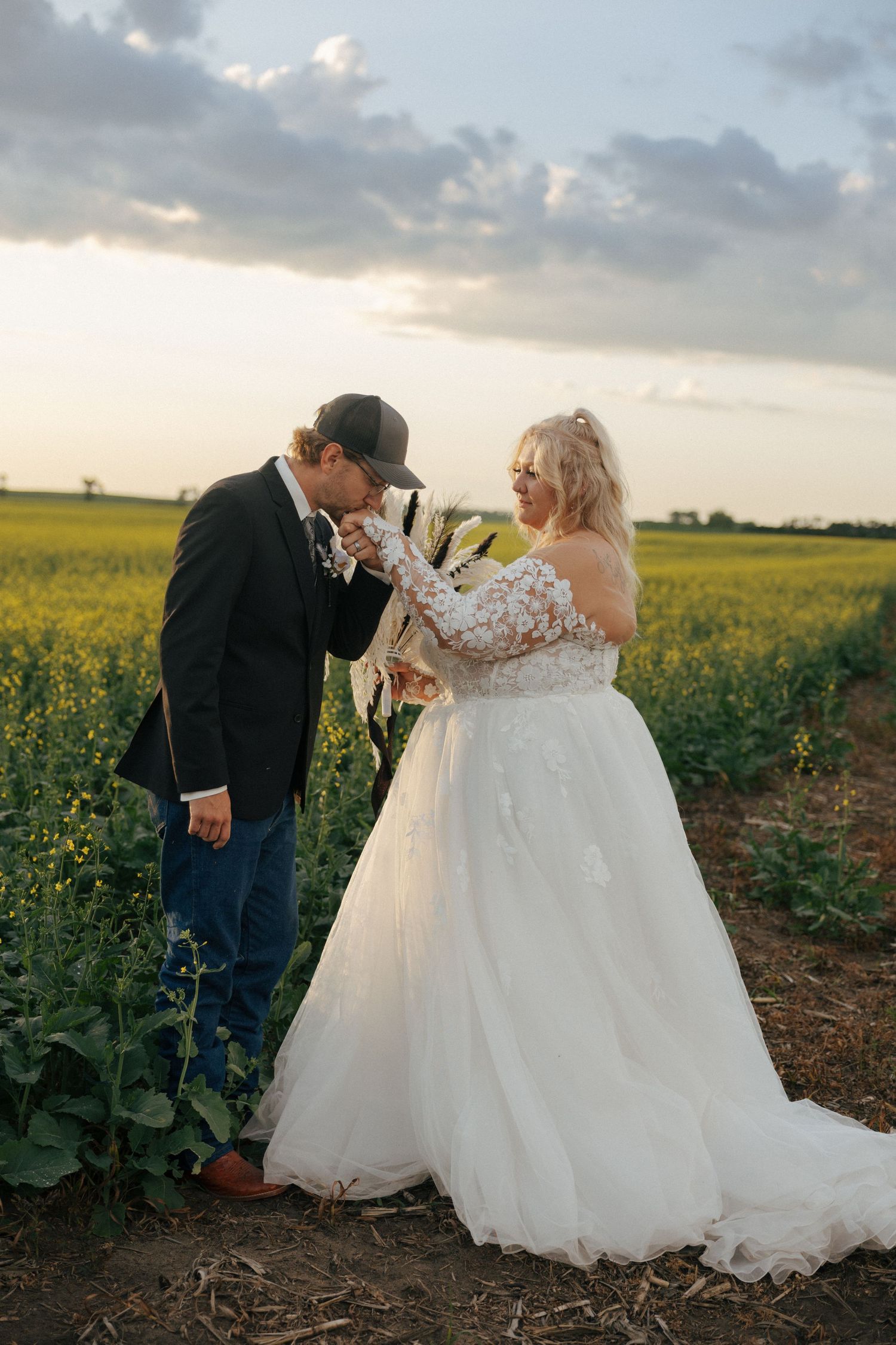 Wedding couple posing in a golden canola field at sunset.