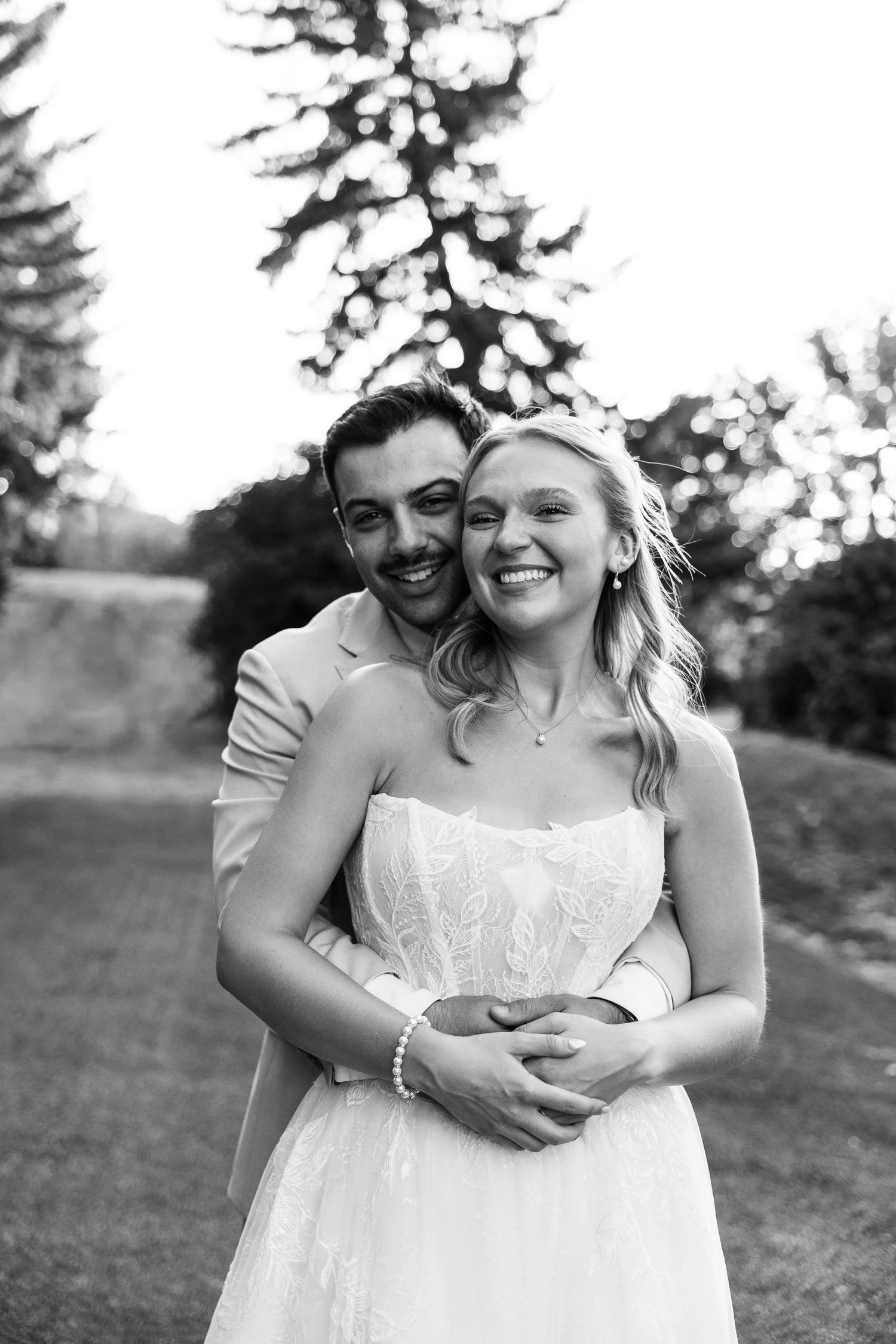 Black and white portrait of smiling bride and groom embracing outdoors on their wedding day.