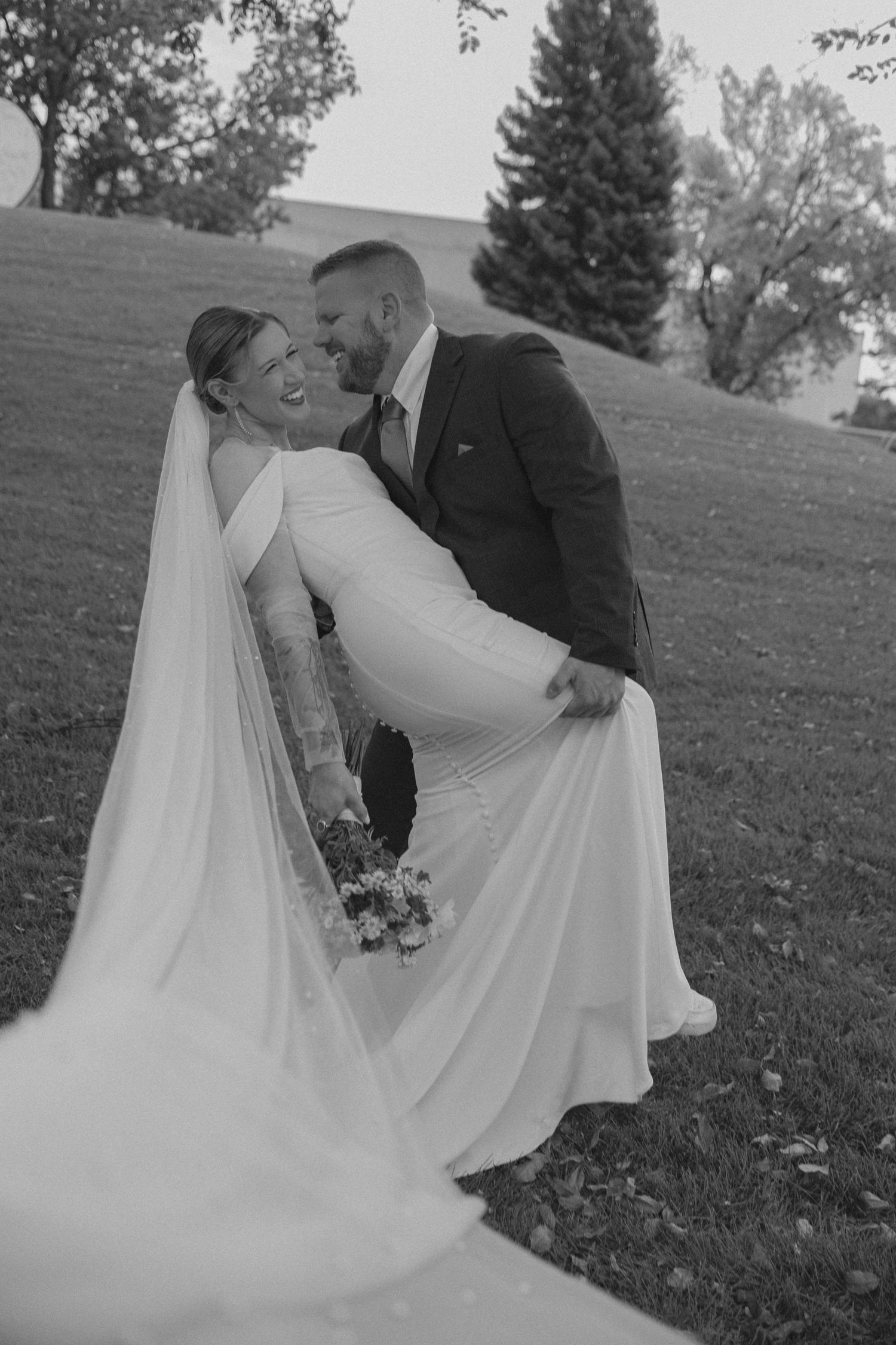 Black and white romantic wedding portraits on a grassy hillside.