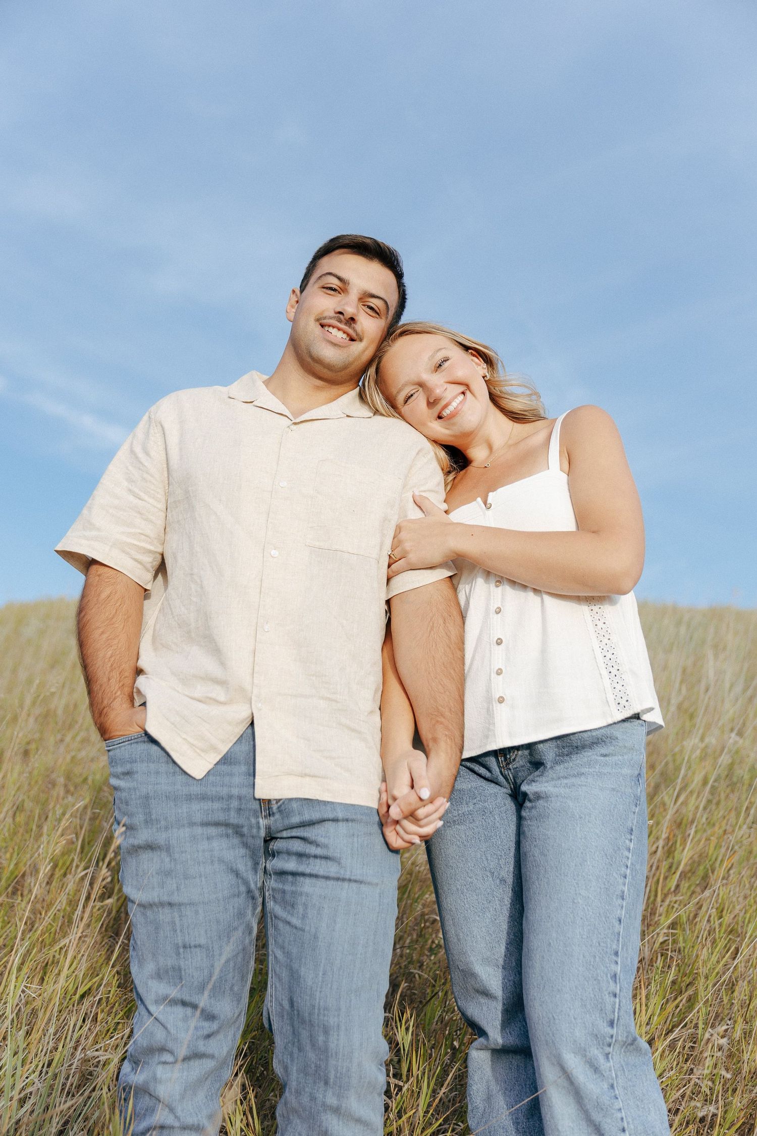 A couple sharing an affectionate moment while standing in a golden grass field.