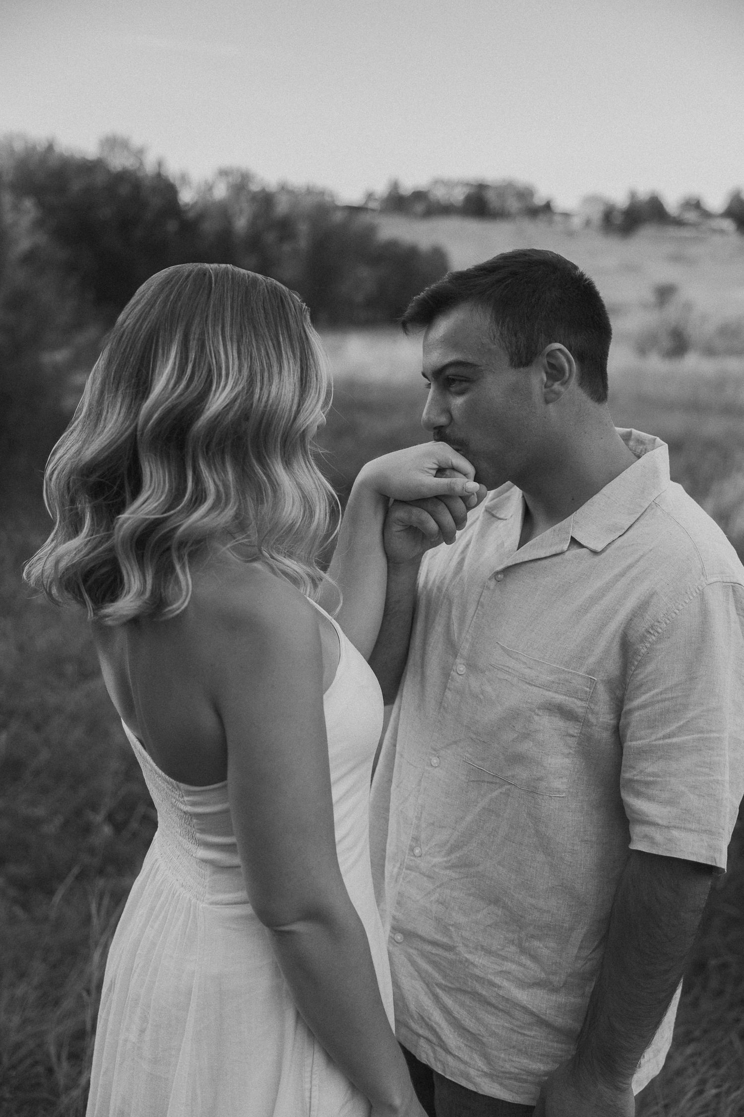 A black and white portrait capturing an intimate moment between a couple in nature.