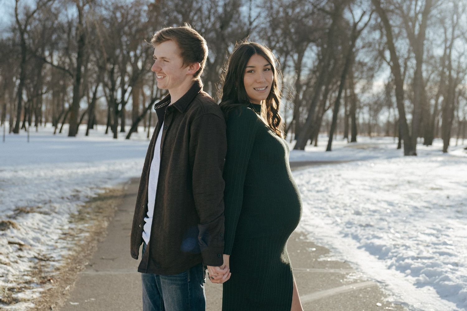 Couple back to back for maternity session in snowy park in Bismarck