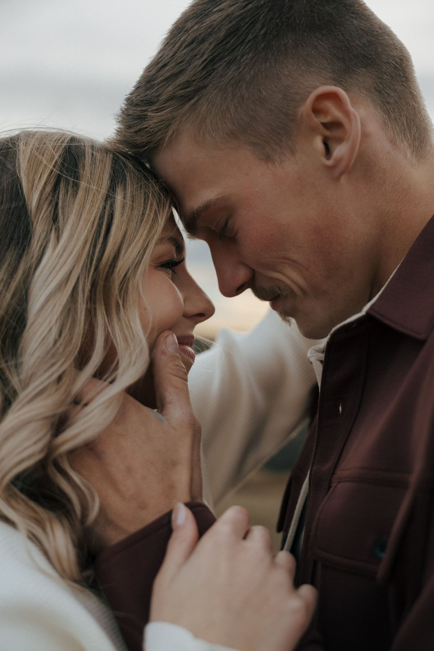 An intimate close-up portrait of a couple sharing a loving moment outdoors.