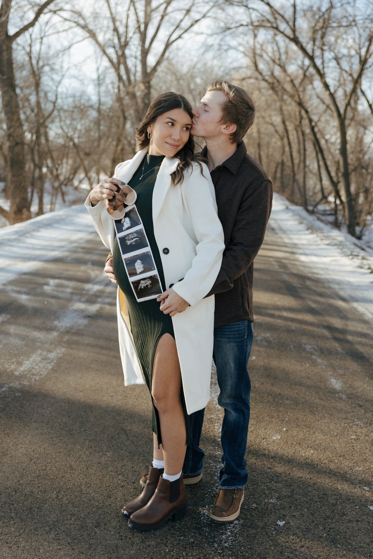 Couple kissing in snowy trees in Bismarck with ultrasound photos