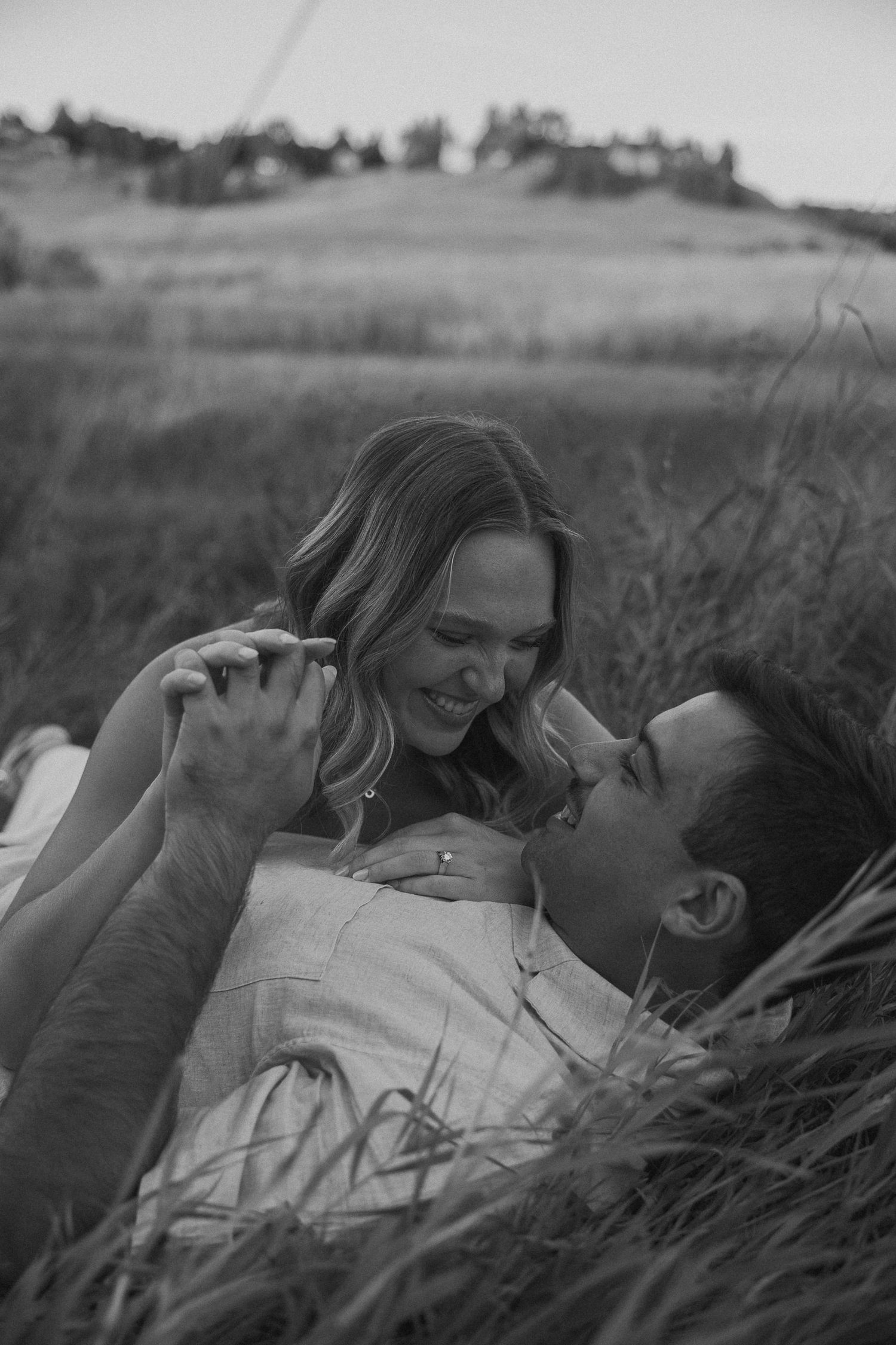A black and white photo captures a tender moment between a couple in a field.