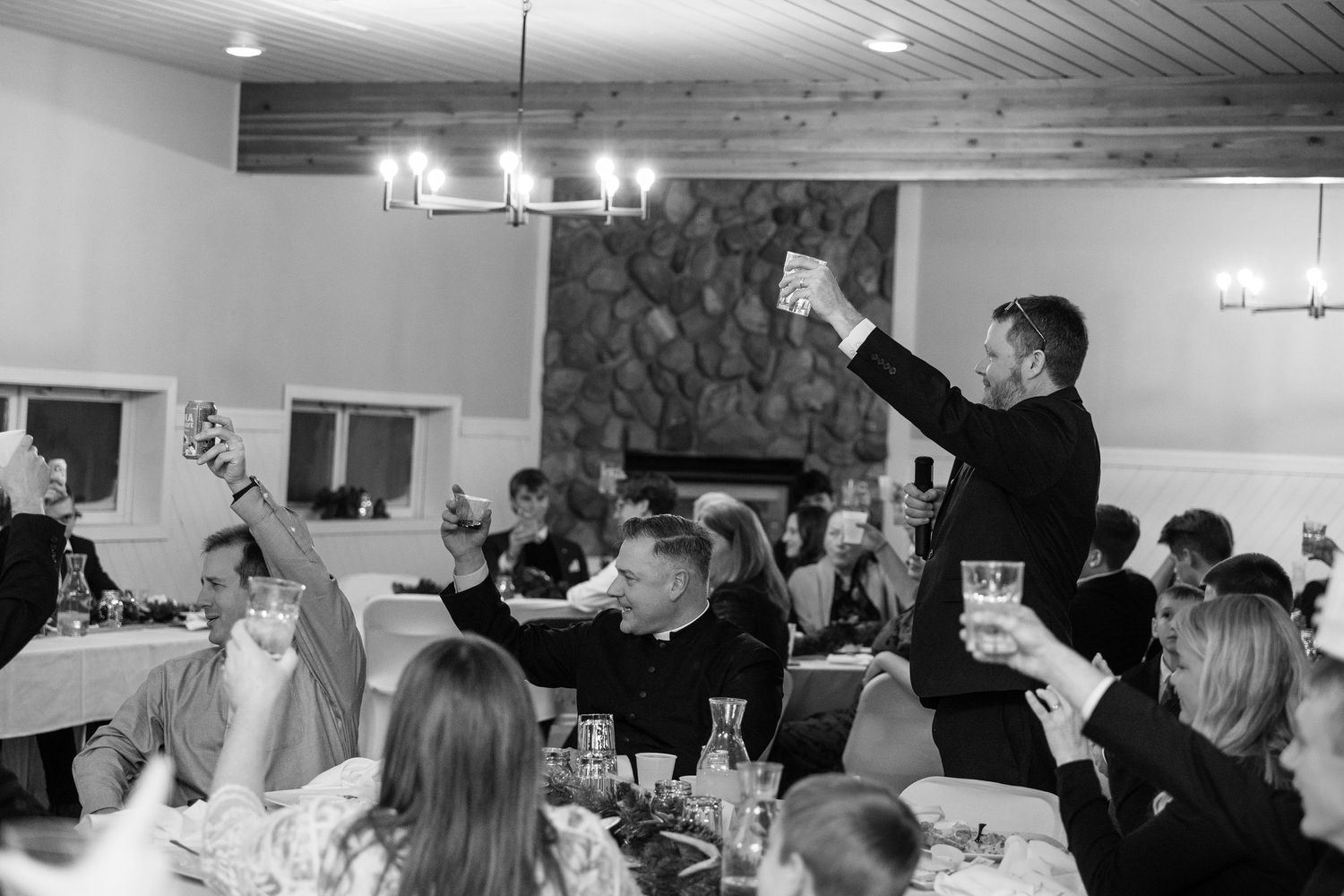 Wedding reception scene with guests seated at tables under ambient lighting.