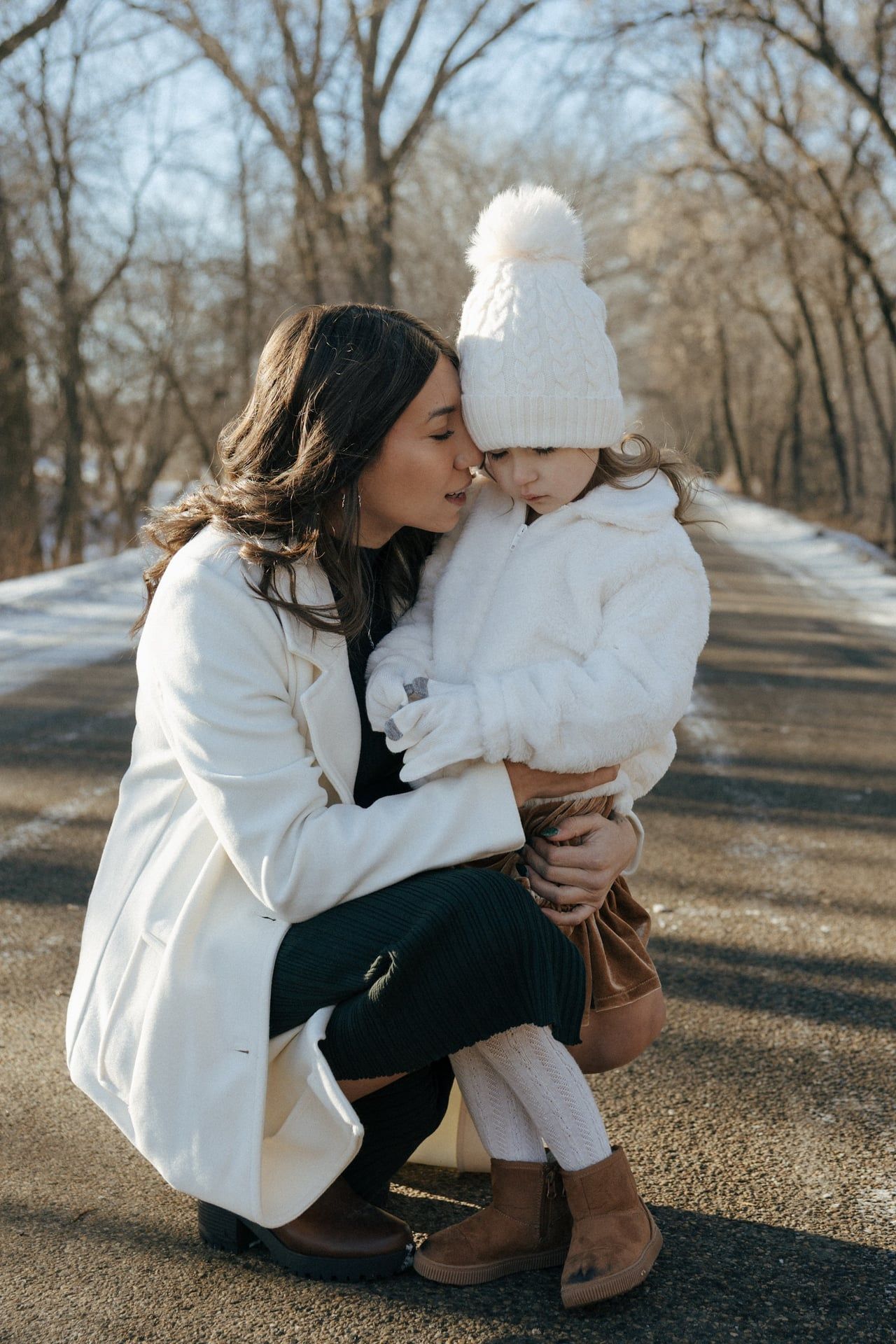 photos of mother to be crouching down next to daughter in snowy trees in Bismarck