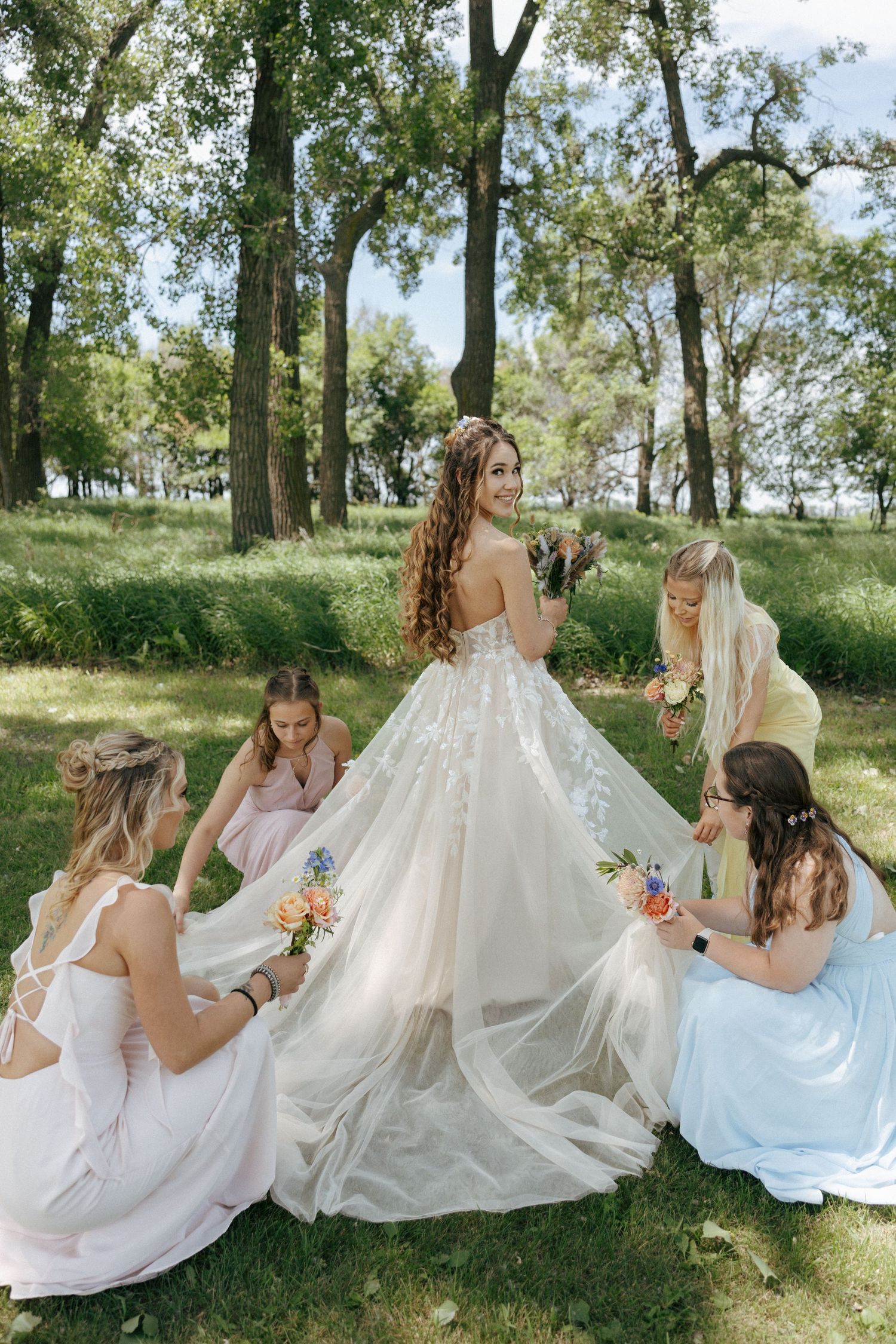 girls helping bride with fluffing her dress on wedding day