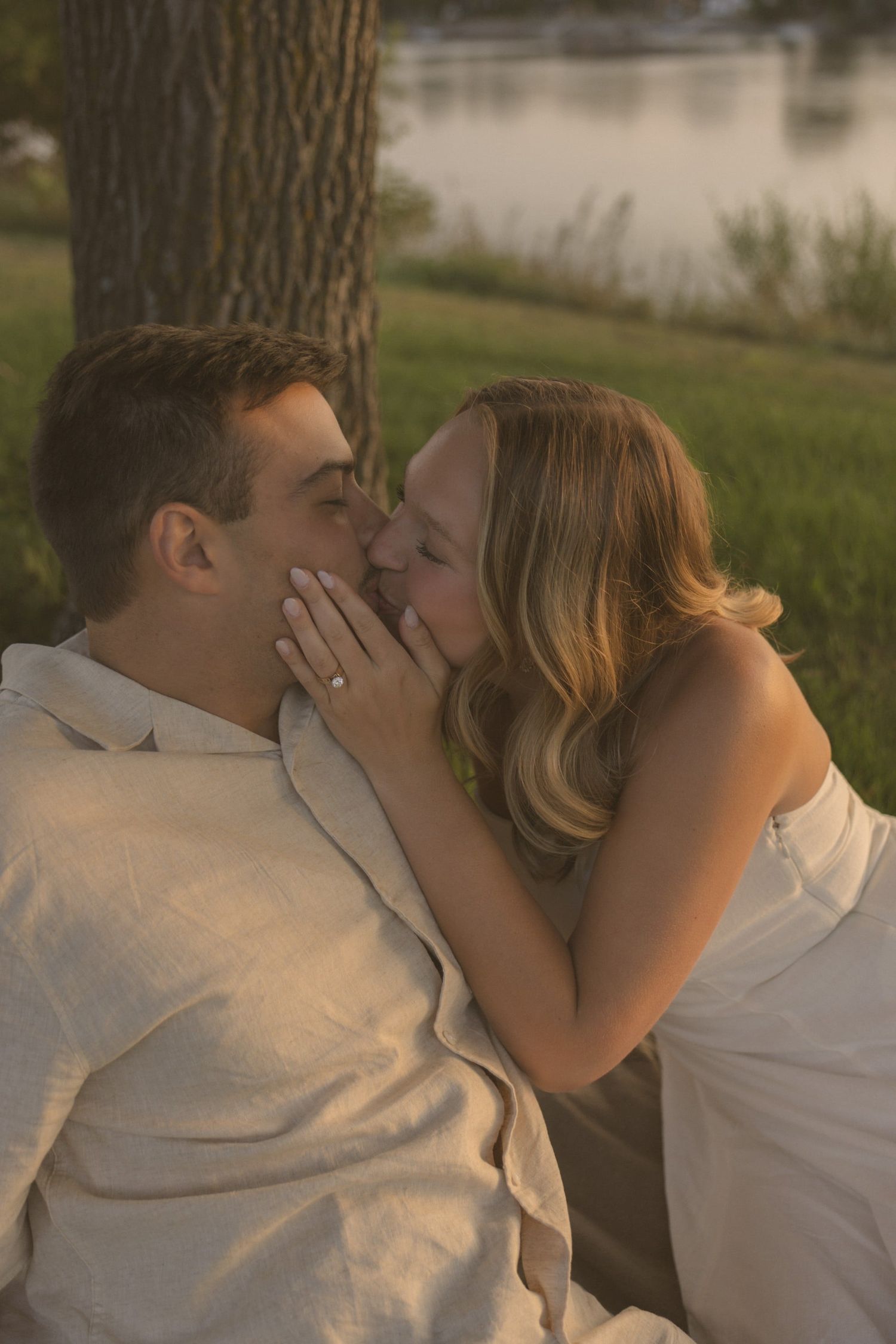 A romantic photo series capturing tender moments between a couple by a tree at sunset.