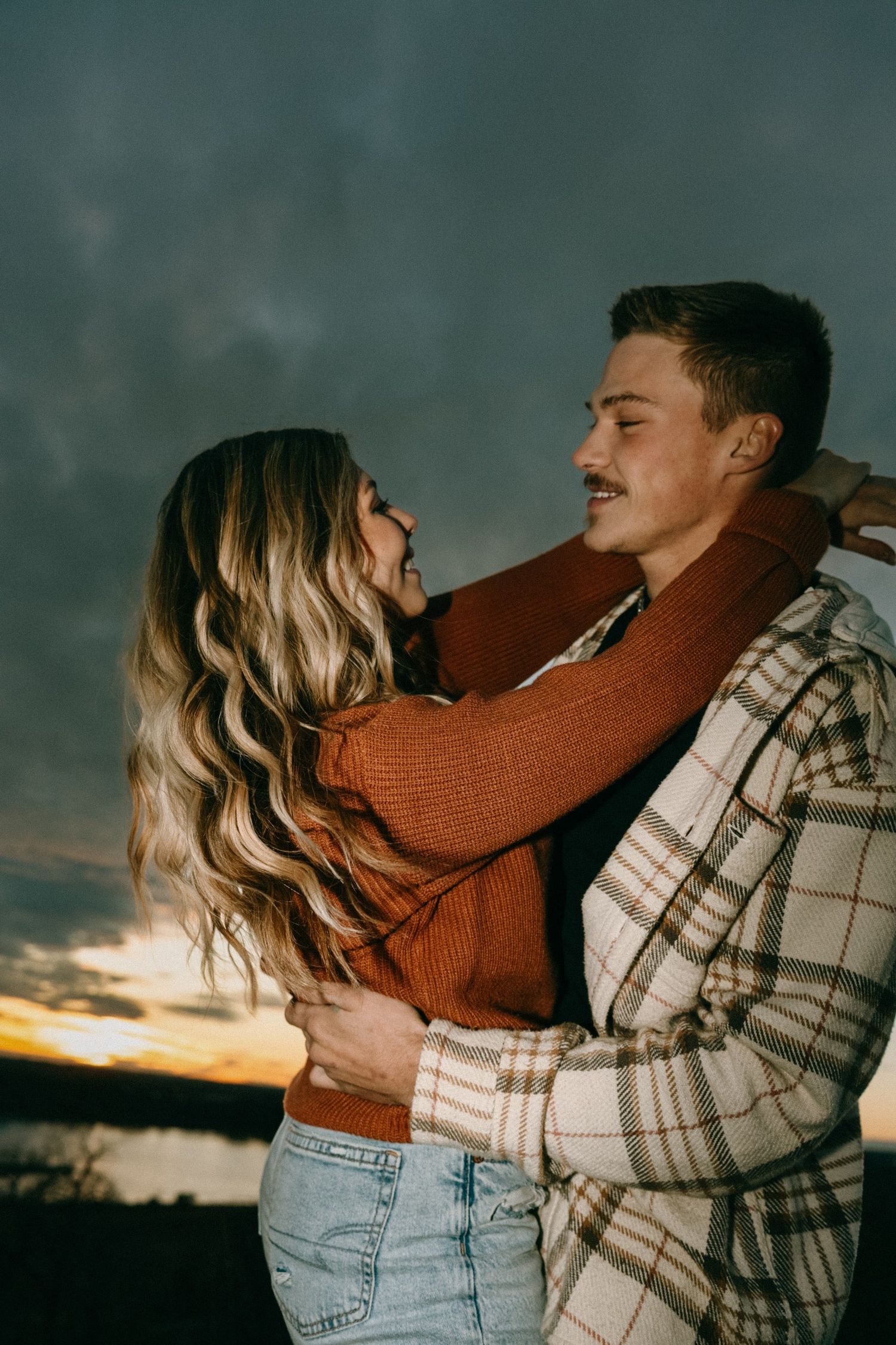 Intimate portrait series of a couple embracing in warm autumn clothing at dusk.