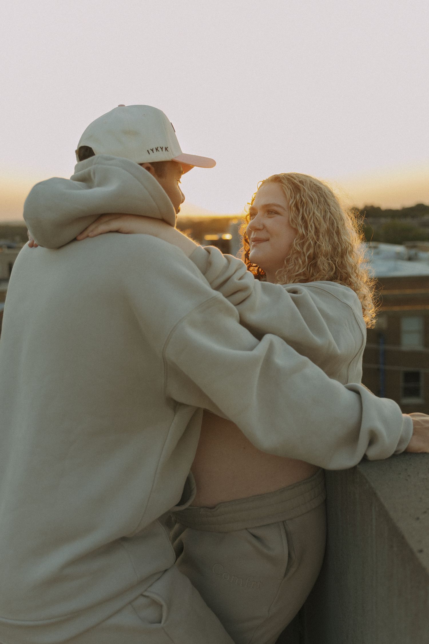 mom and dad to be embracing on rooftop during sunset for maternity session