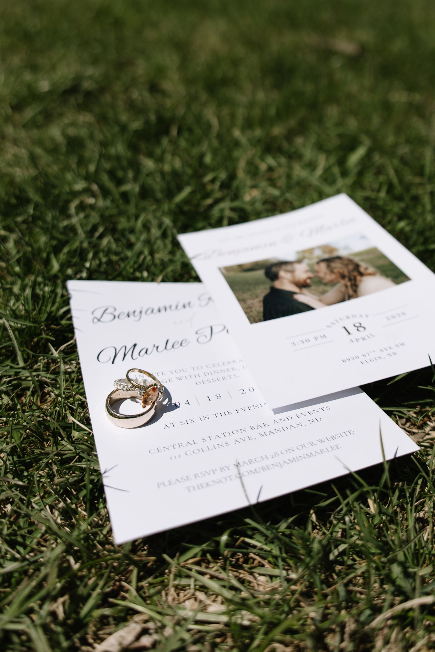 Wedding invitation for Benjamin and Martee on grass with gold engagement rings and couple photo.