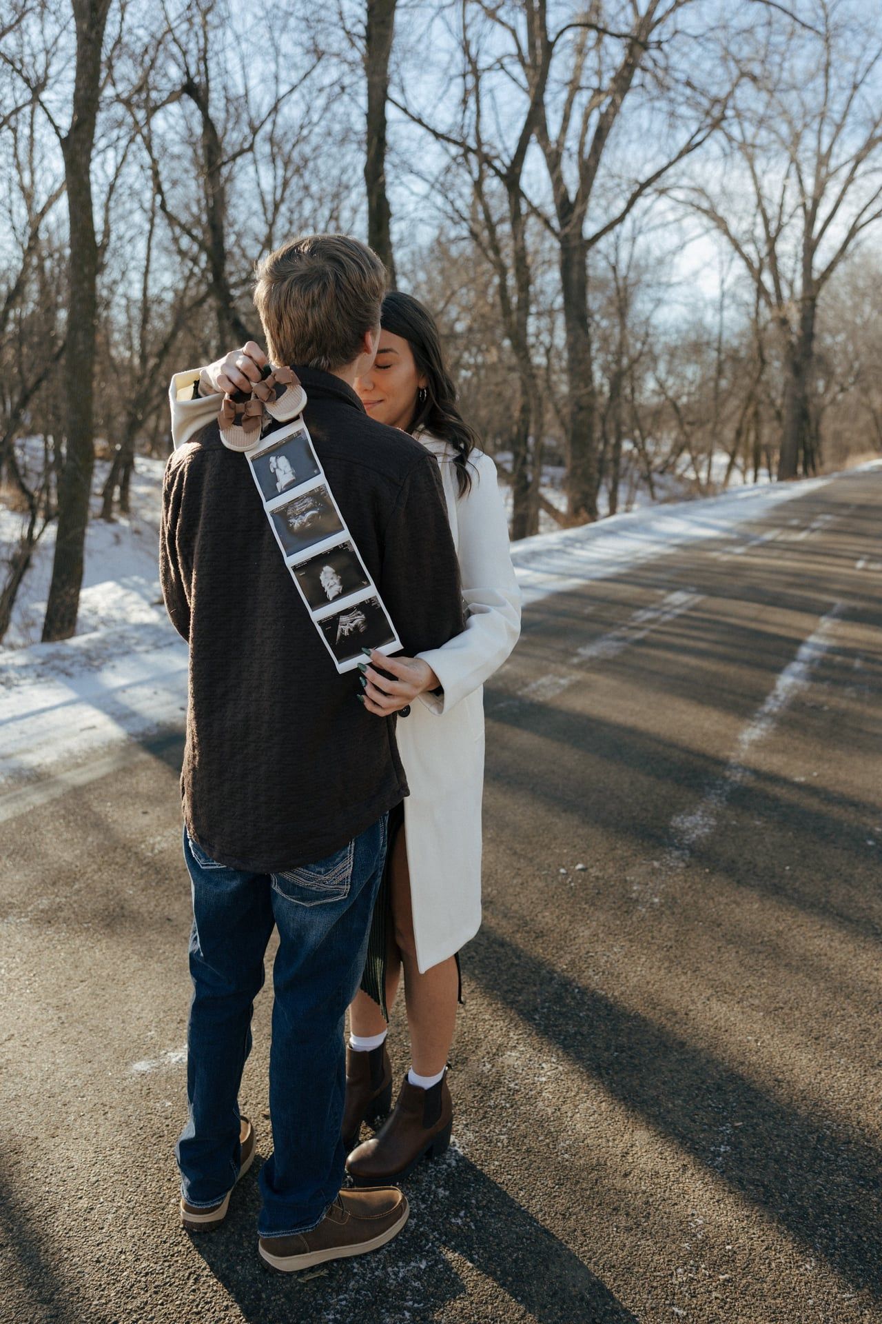 Couple kissing in snowy trees in Bismarck with ultrasound photos