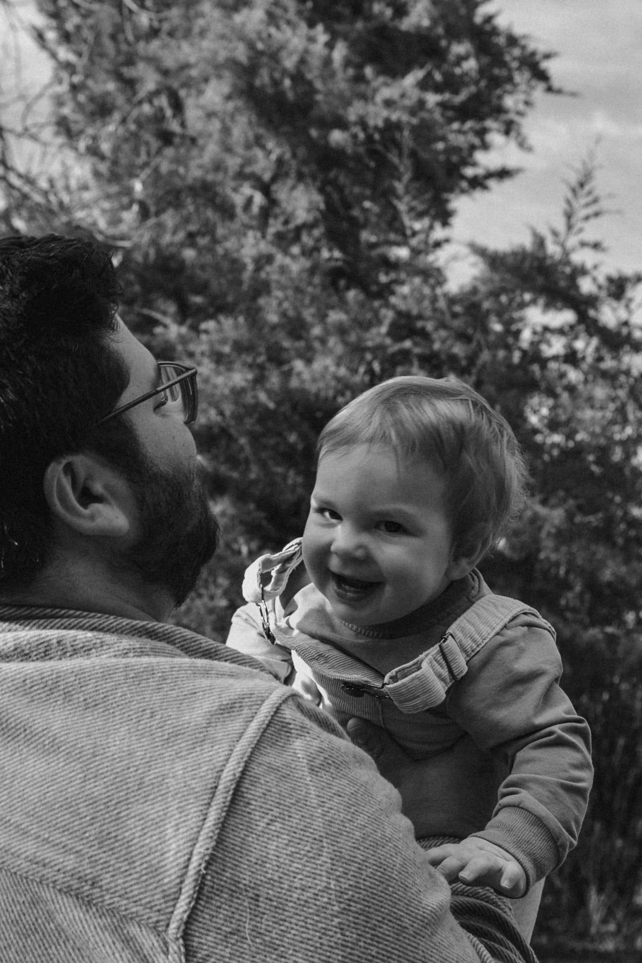 dad throwing baby in the air and holding him as he laughs and giggles