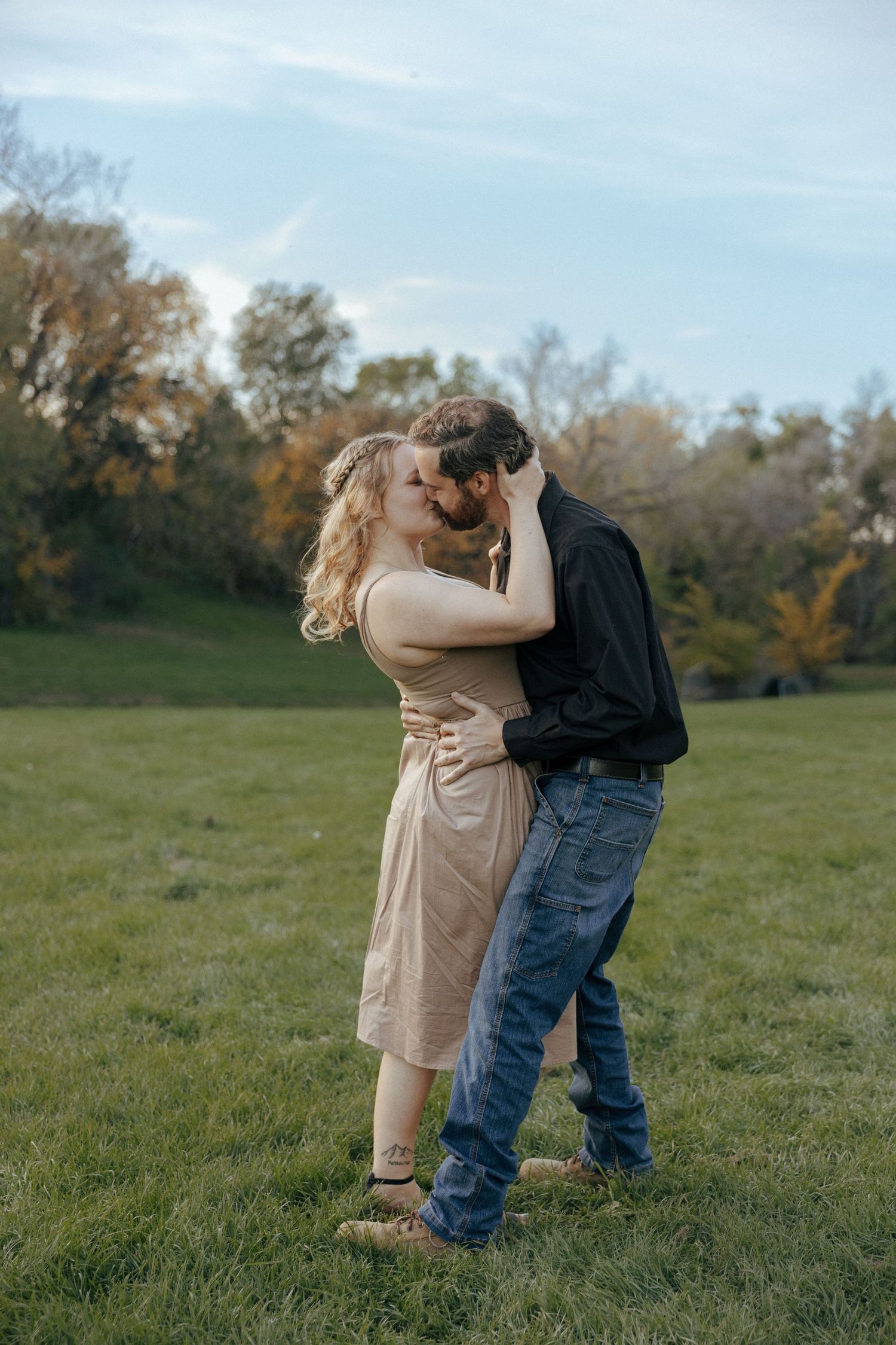 couple kissing in grassy field in Bismarck