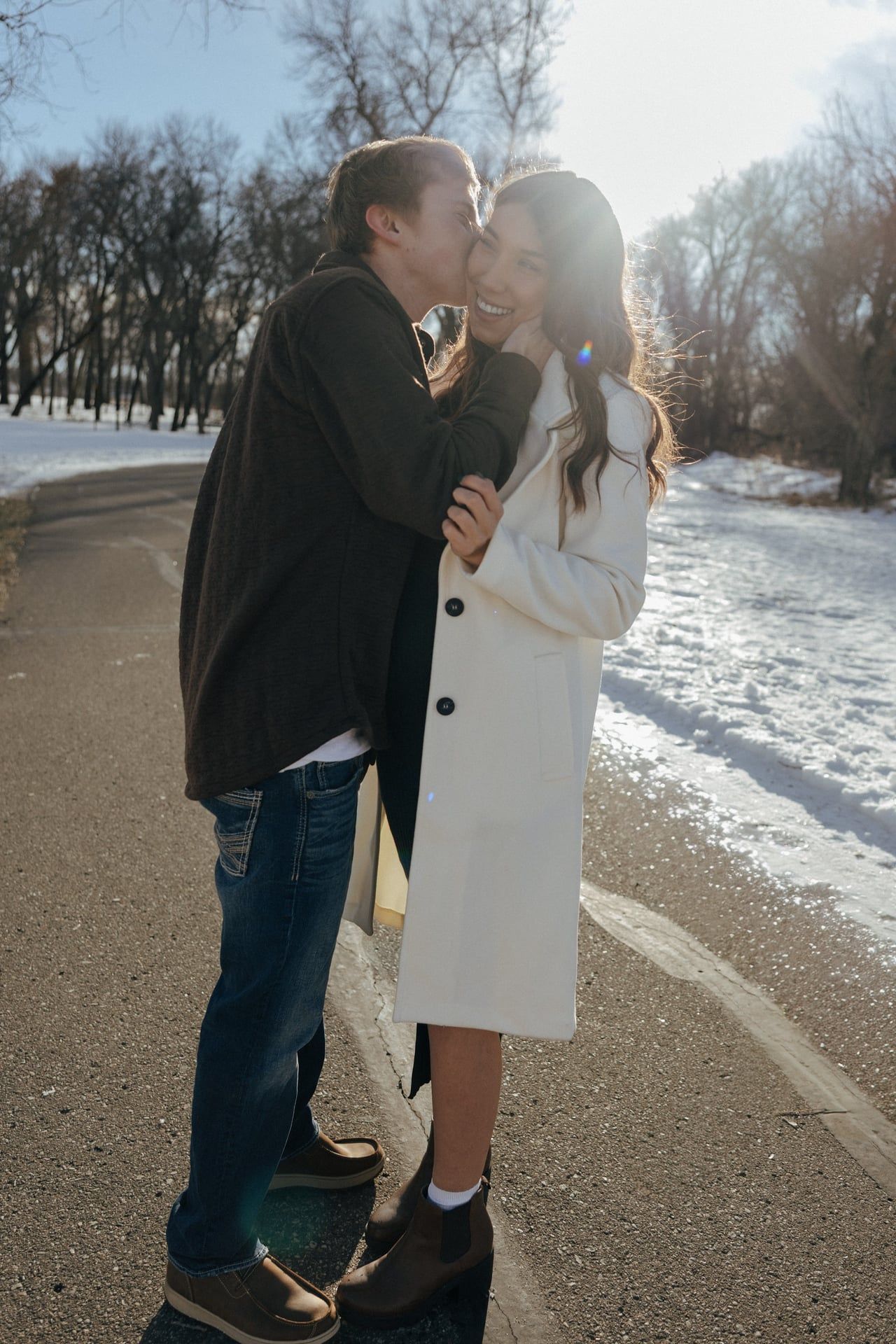 Man kissing girl on cheek in snowy park in Bismarck