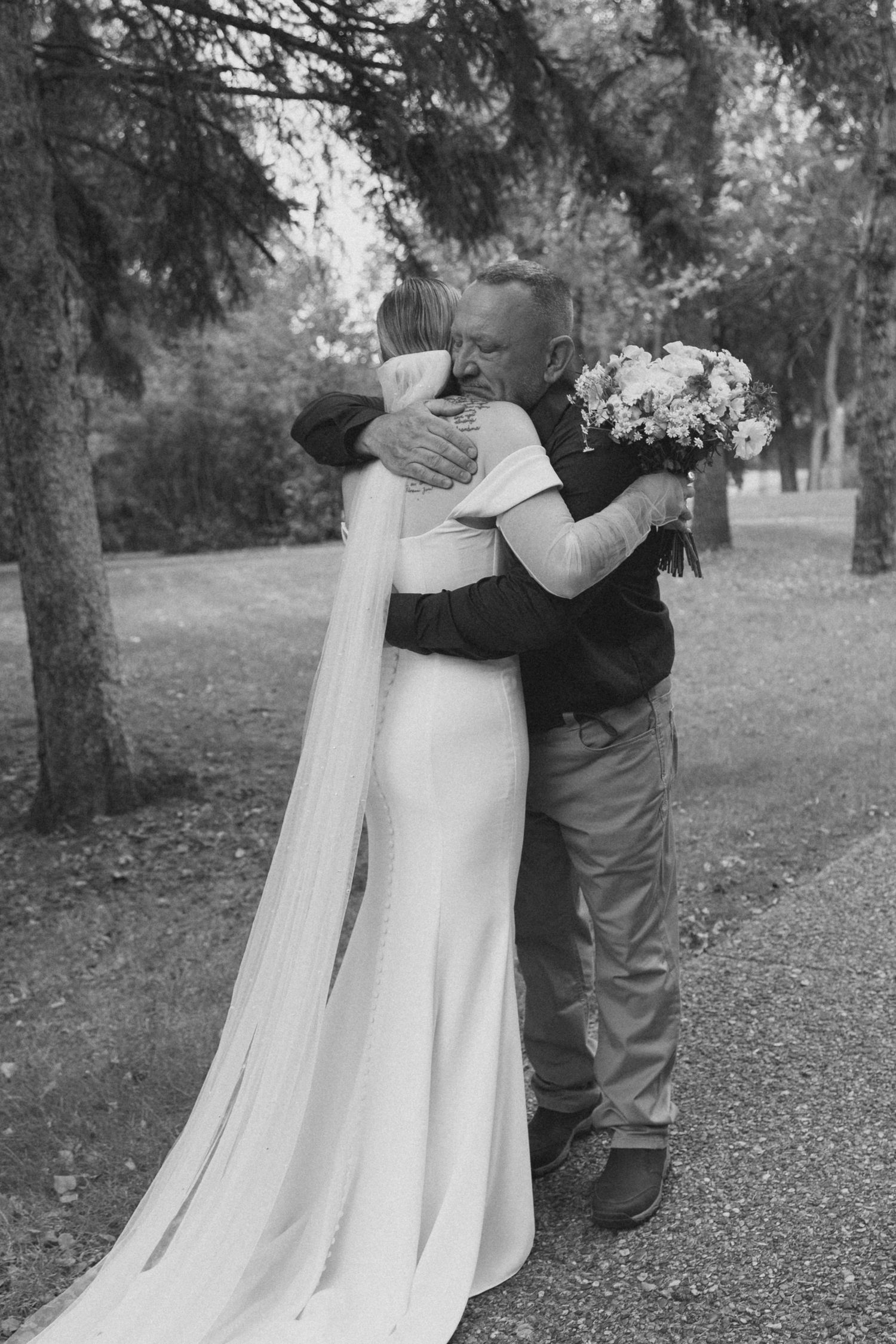 Black and white wedding photos showing tender moments between a couple on a tree-lined path.