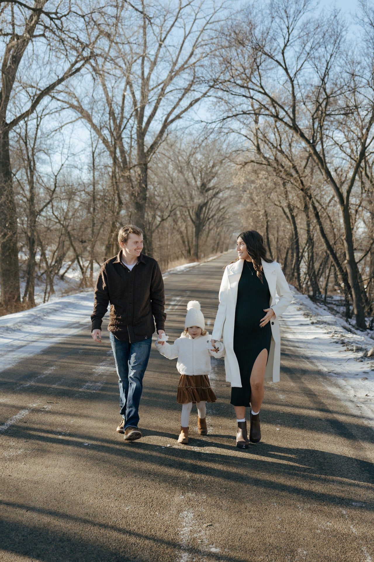 photos of family walking holding hands in snowy trees in Bismarck
