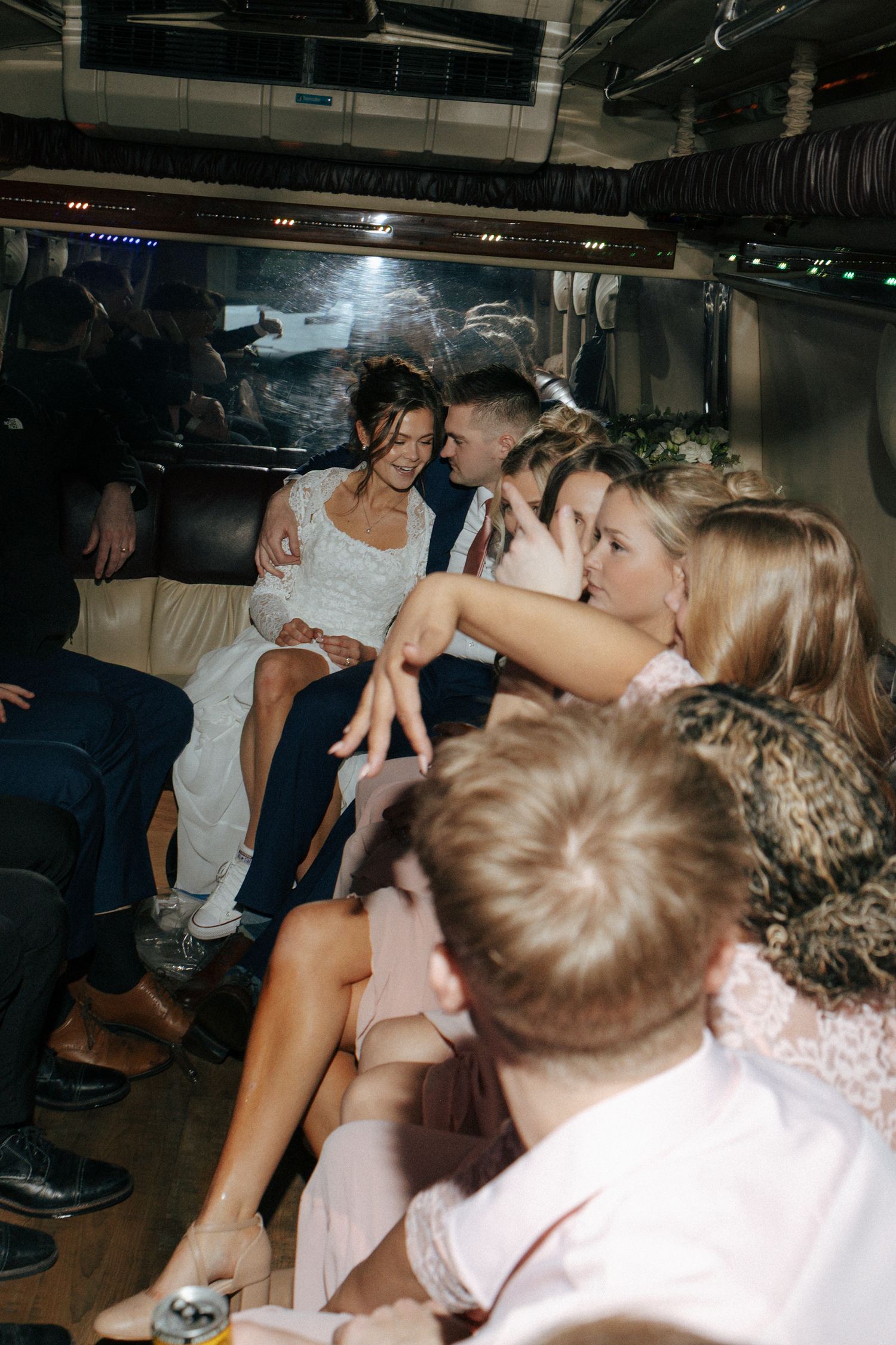 bride and groom talking on party bus with wedding party having fun