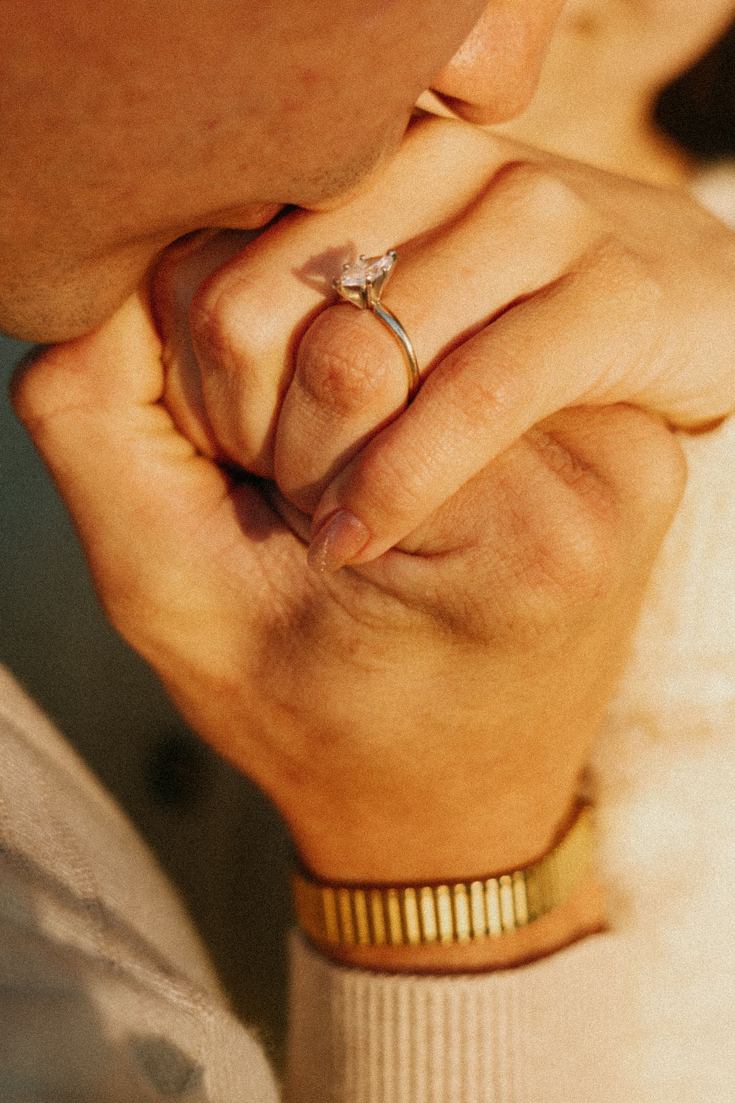 man kissing hand of women with engagement ring