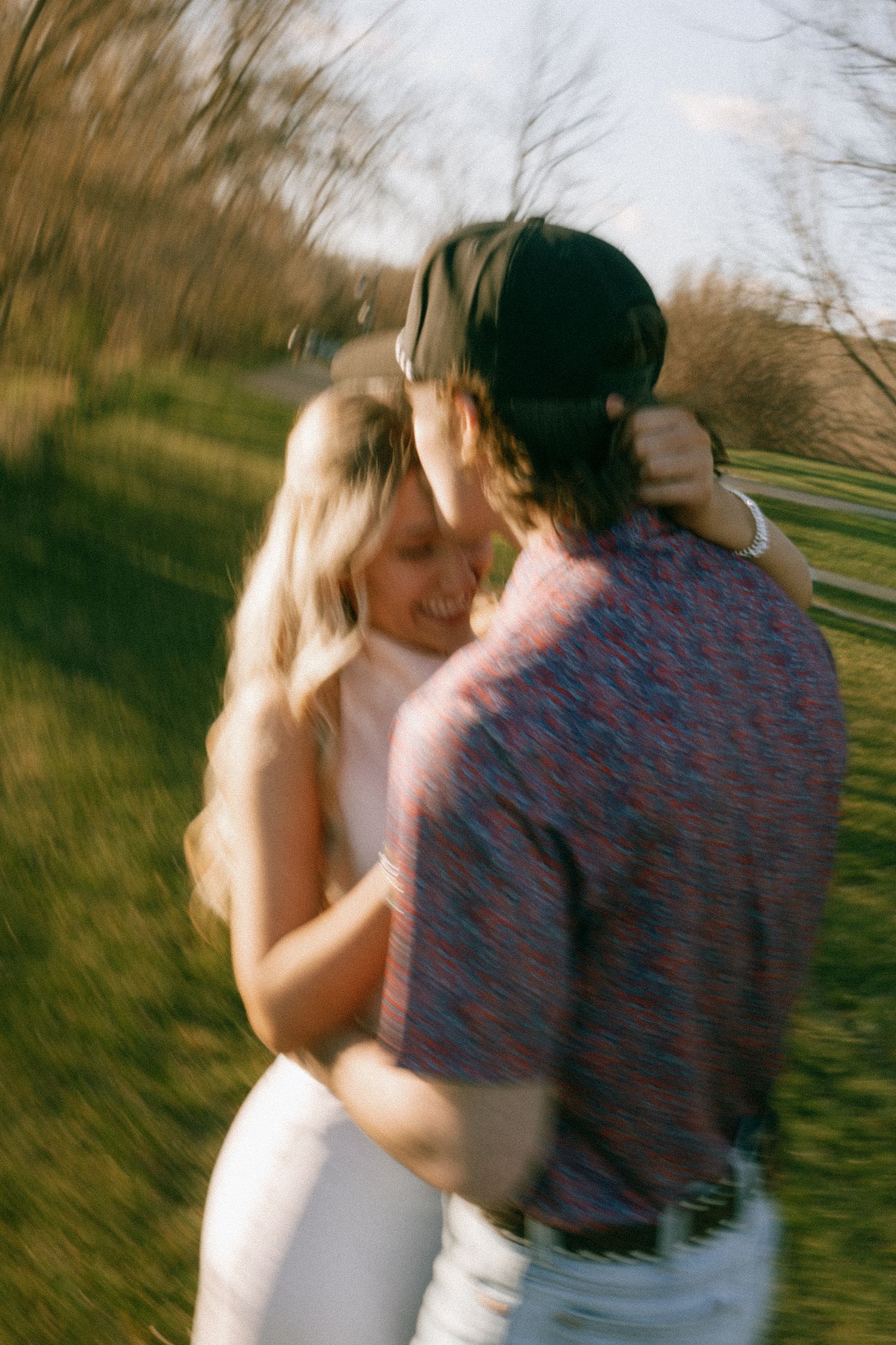 Blurred motion shot of a couple embracing and dancing outdoors in golden hour light.