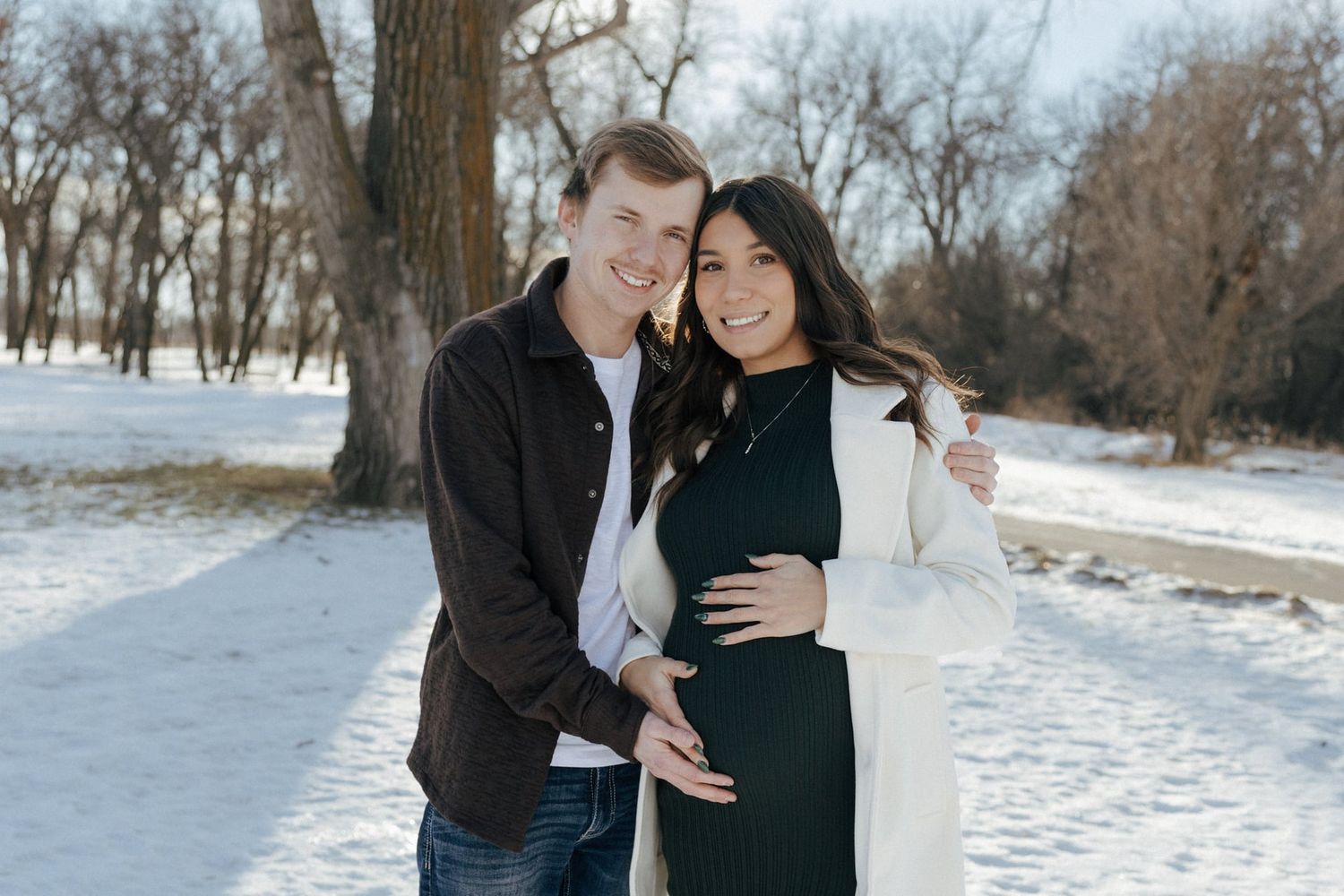 Couple smiling at camera for winter maternity session