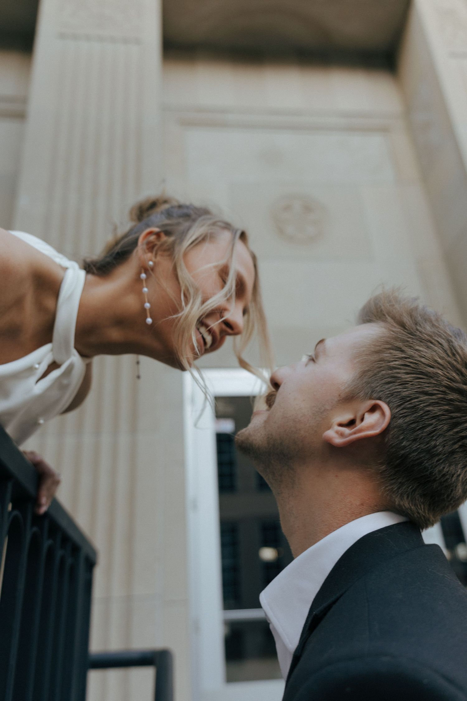 girl leaning down to kiss man for engagement photos downtown Bismarck