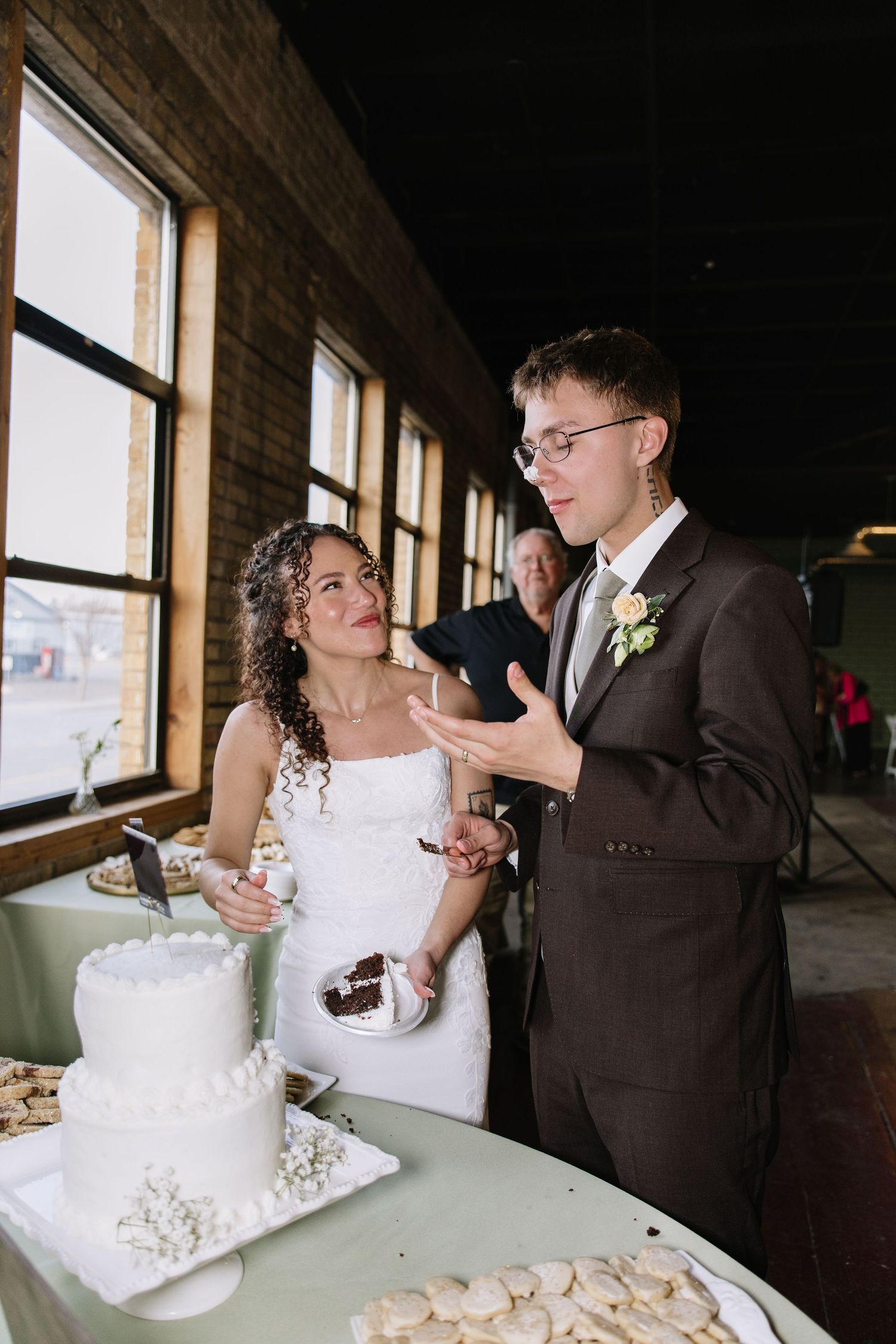 Bride and groom cutting their white wedding cake at a rustic venue reception.