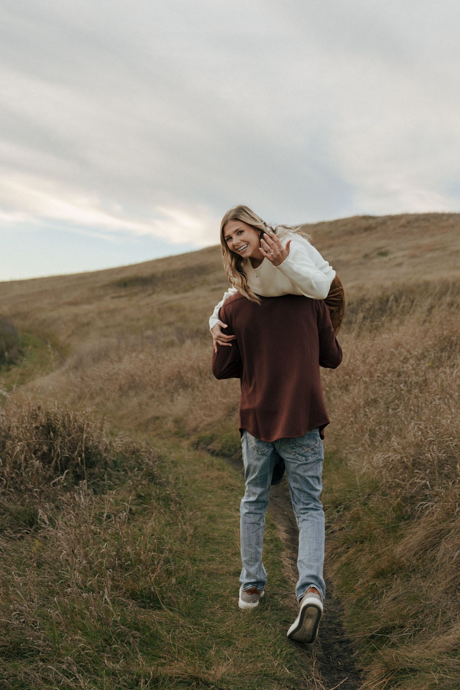 A person in casual autumn attire stands on a natural hiking trail.