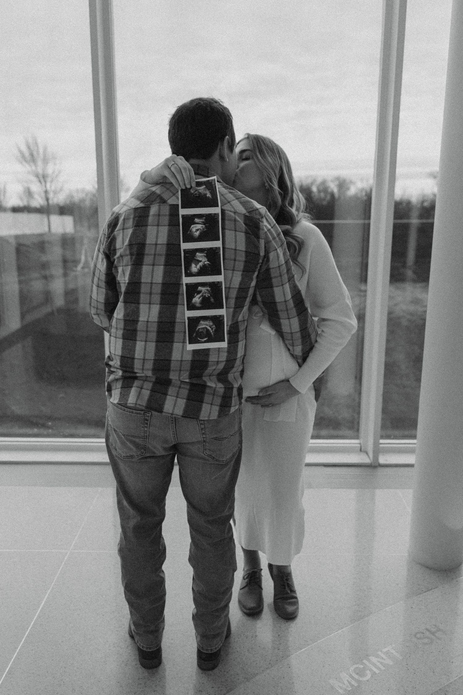 couple holding ultrasound photos and kissing in the Heritage Center in Bismarck