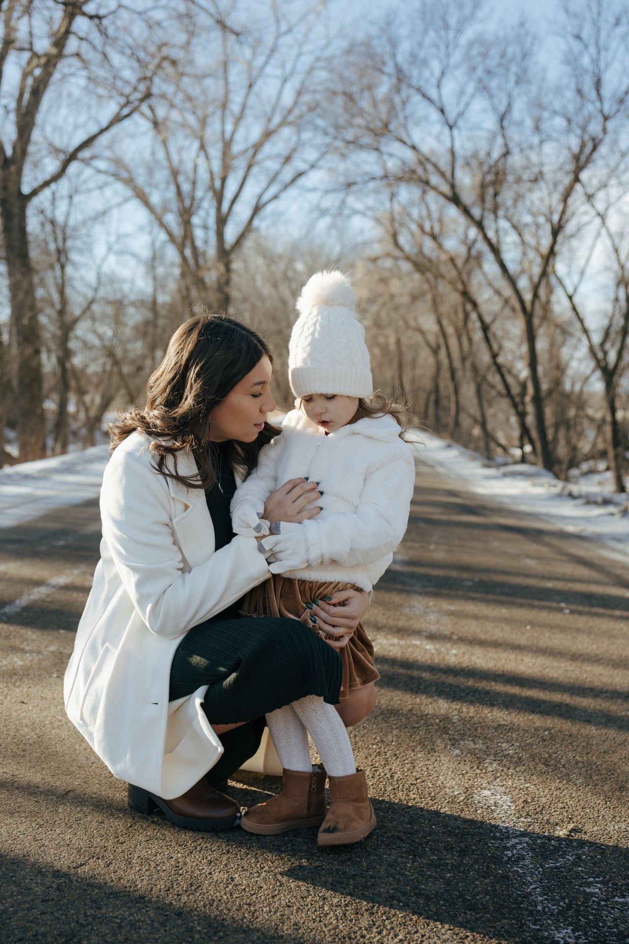 photos of mother to be crouching down next to daughter in snowy trees in Bismarck
