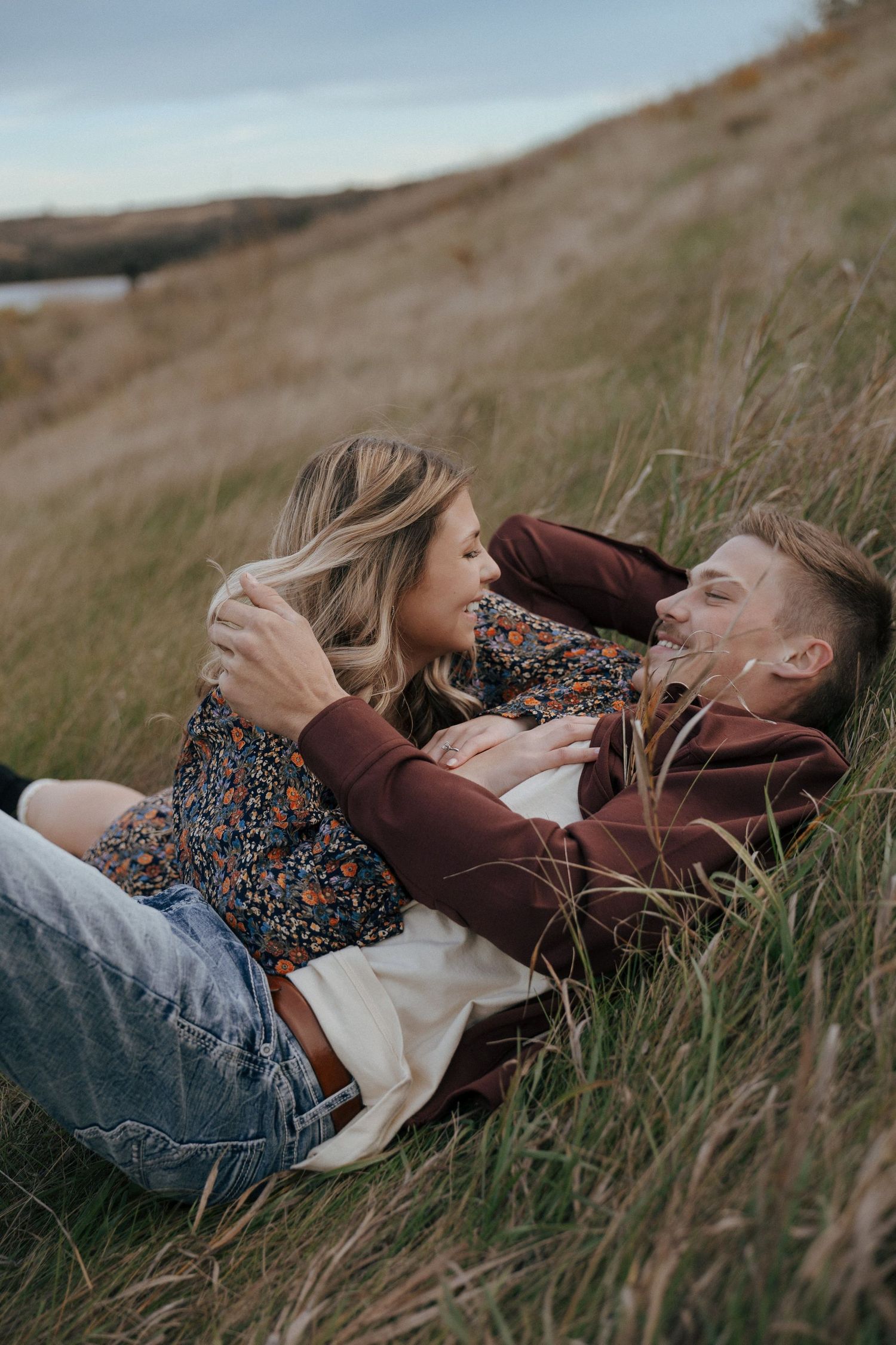 Couple sharing tender moment while lying in autumn field grass.