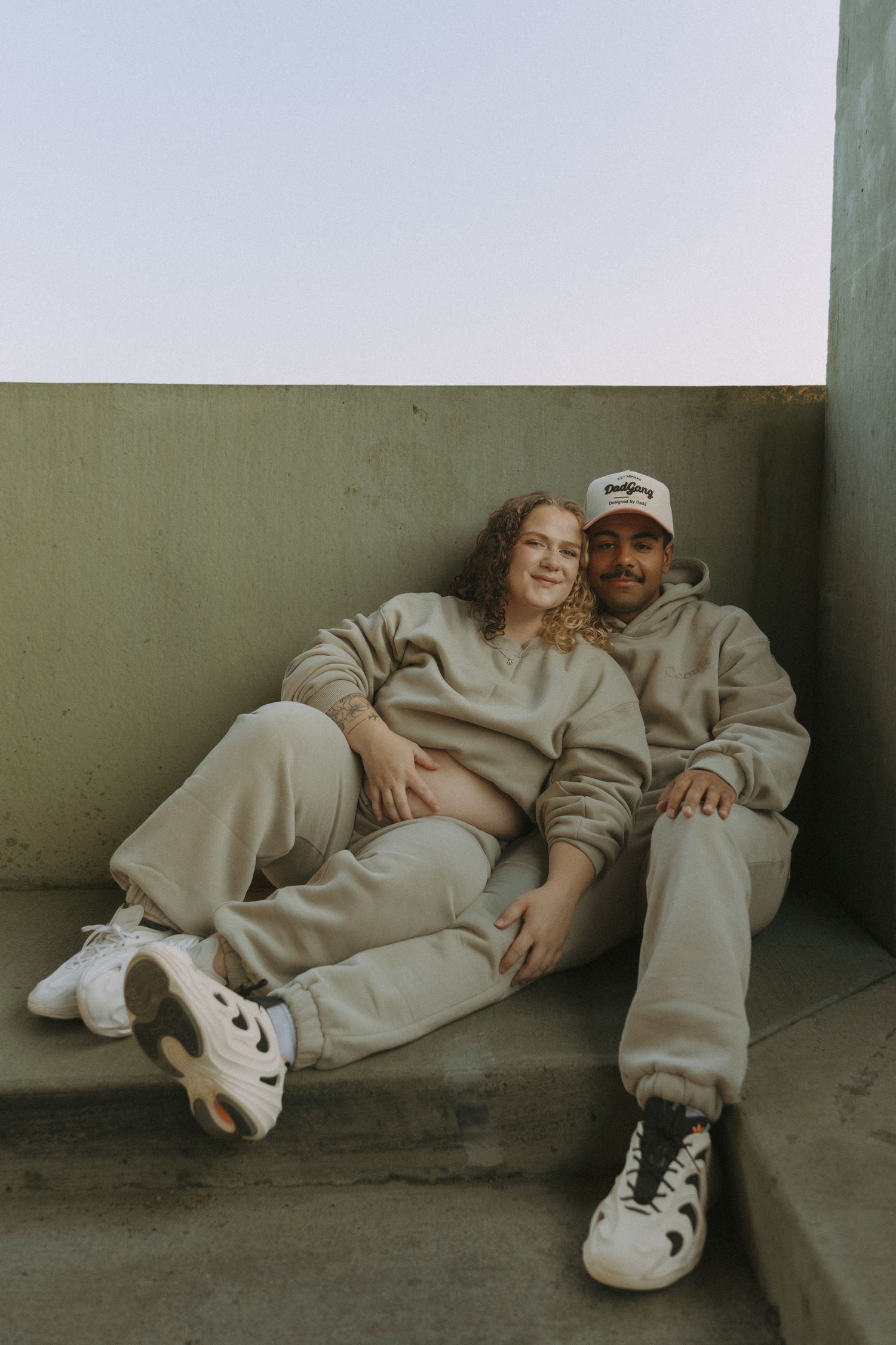 couple smiling at camera while holding baby bump for maternity session downtown Bismarck