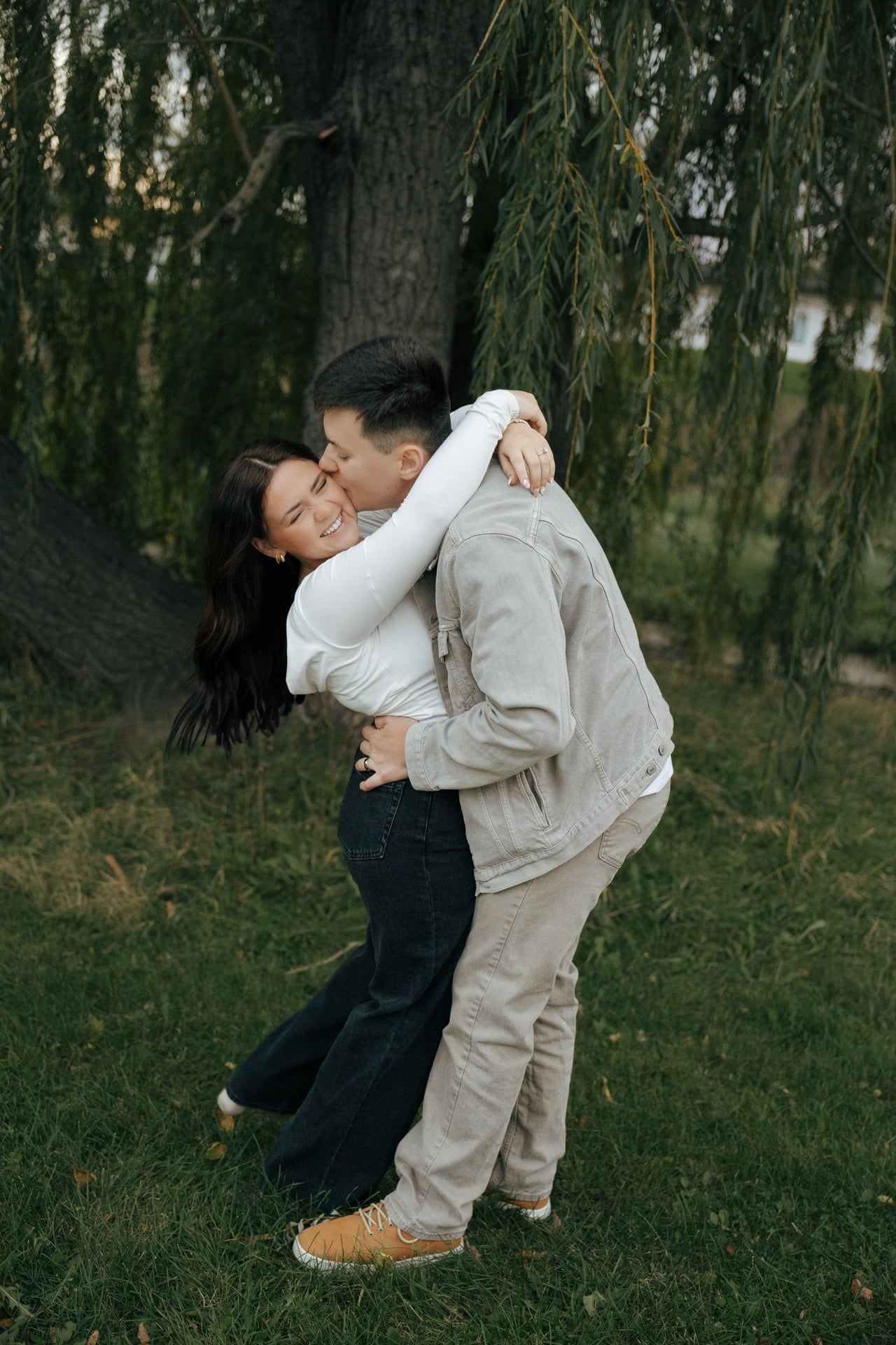 couple kissing with man kissing her cheek as she laughs for engagement photos
