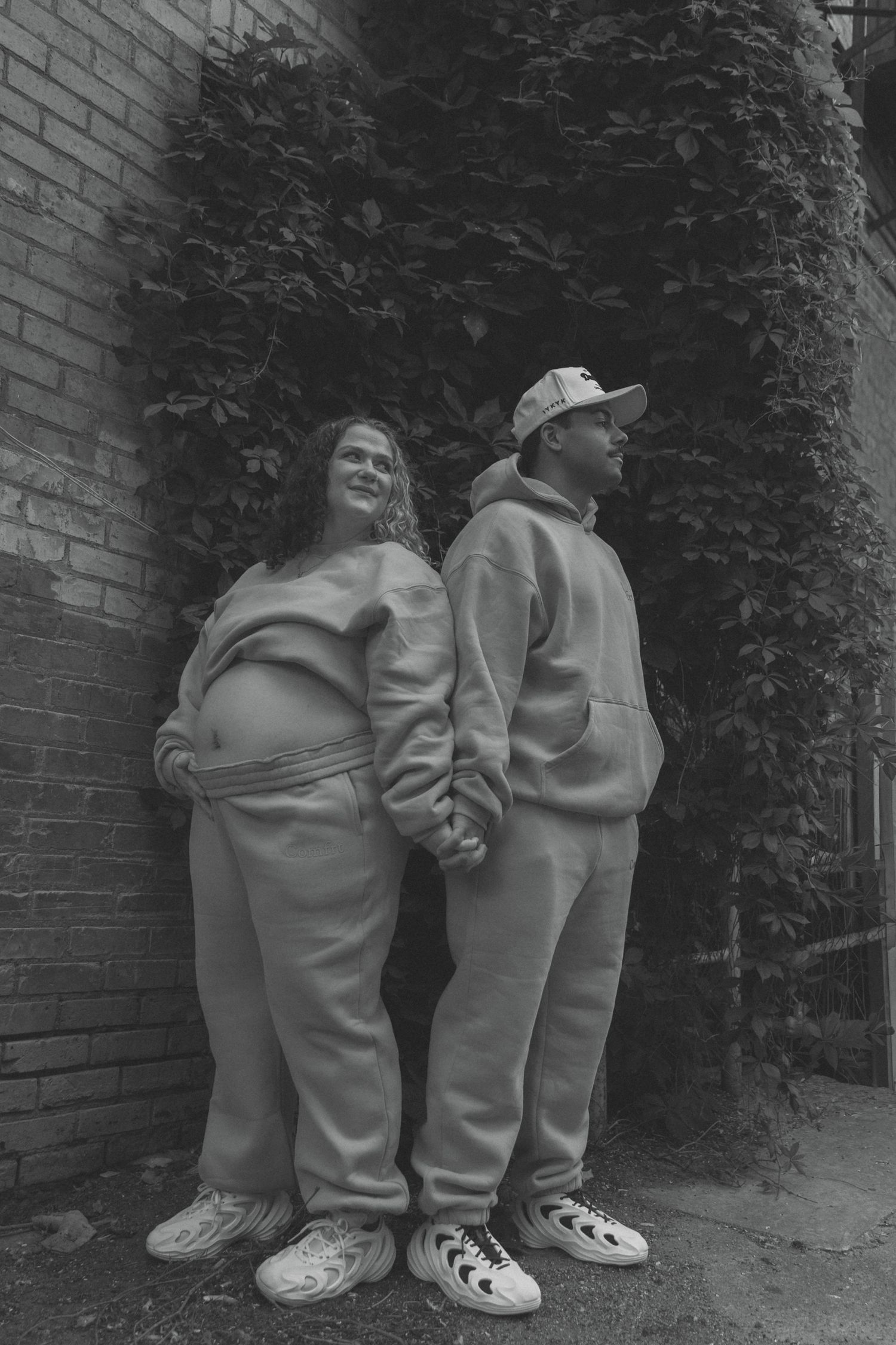 couple holding hands while holding baby bump for maternity session downtown Bismarck