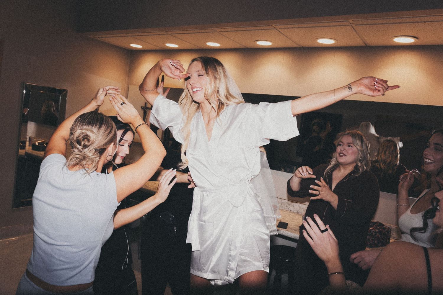 bride getting ready with the girls dancing up on a chair