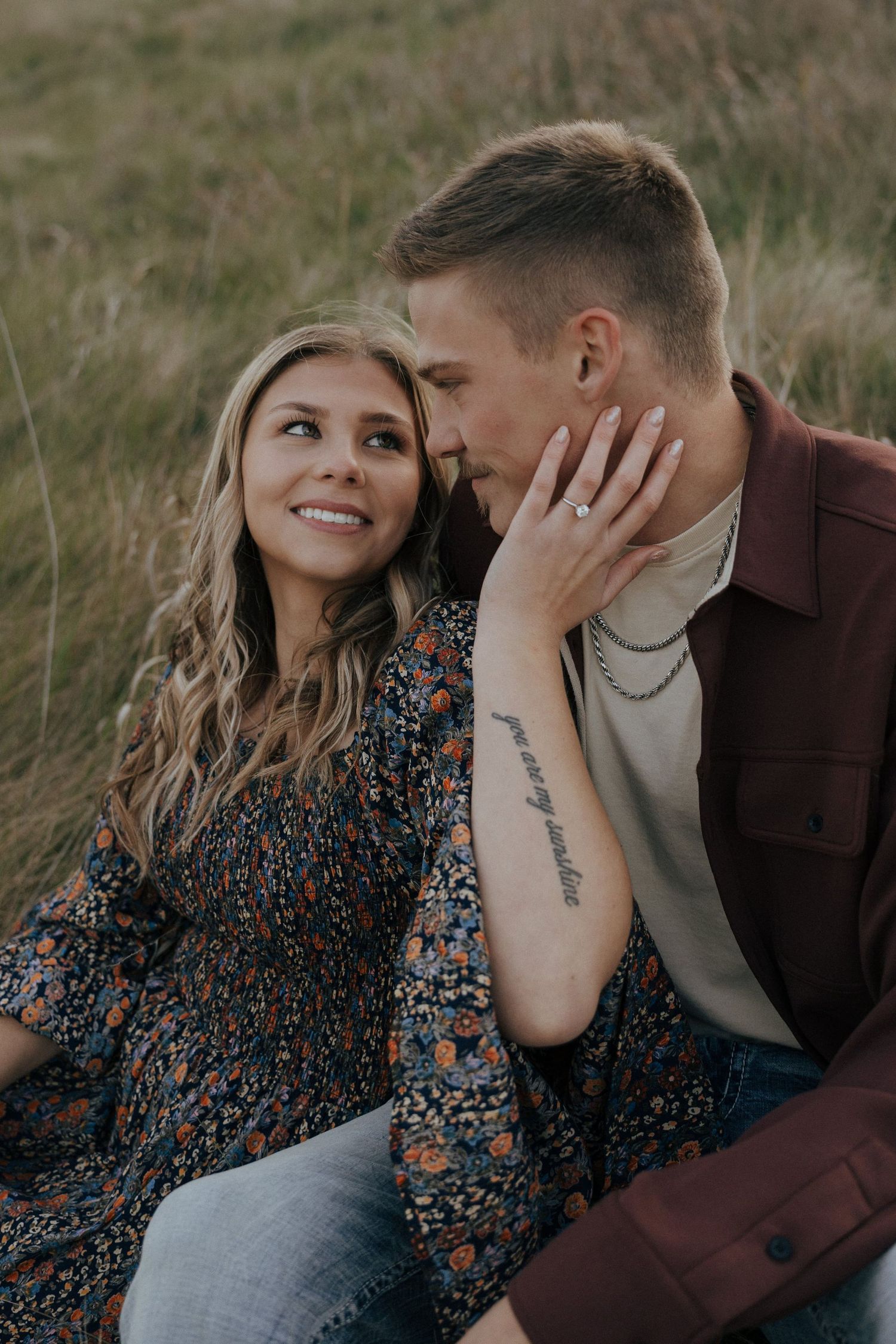 Close-up of couple sharing intimate moment on grassy hillside.