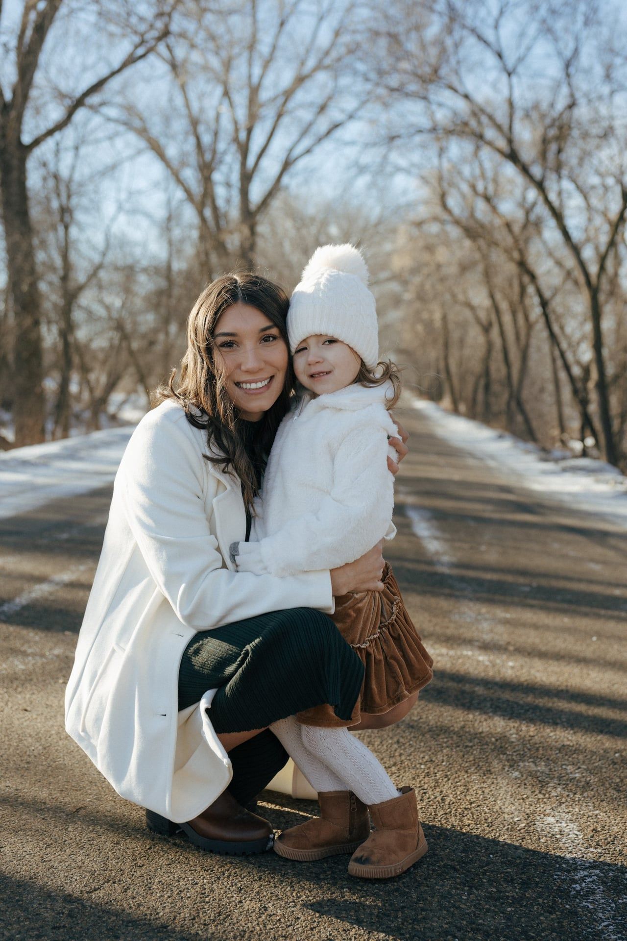photos of mother to be crouching down next to daughter in snowy trees in Bismarck