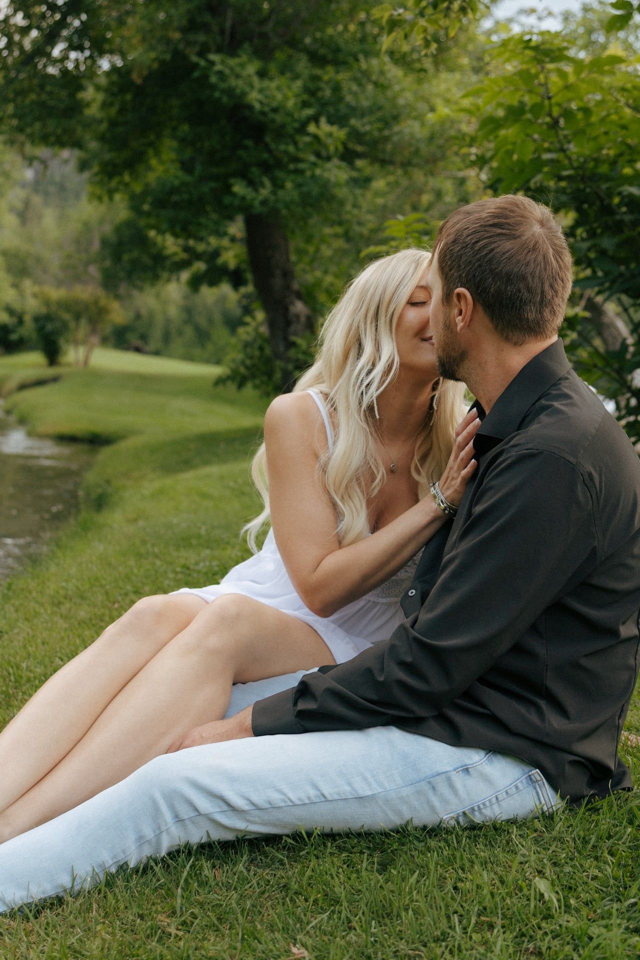 couple kissing each other in black hills for engagement session by water stream